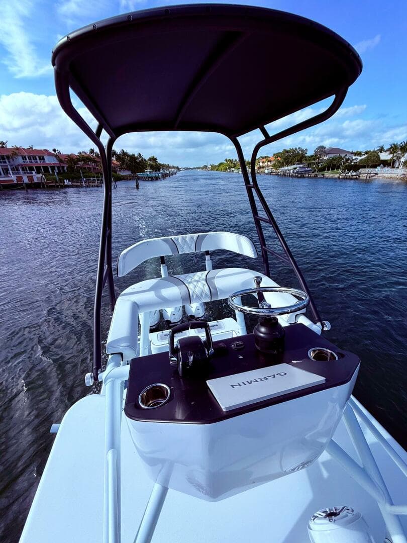2024 Contender 39 ST boat on a scenic waterway, featuring a sleek helm and canopy.