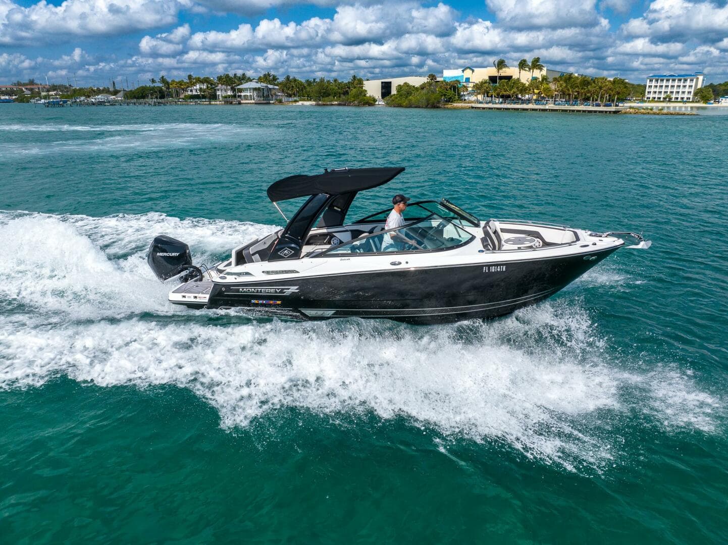 2023 Monterey 255 Super Sport boat cruising on turquoise water under a partly cloudy sky.
