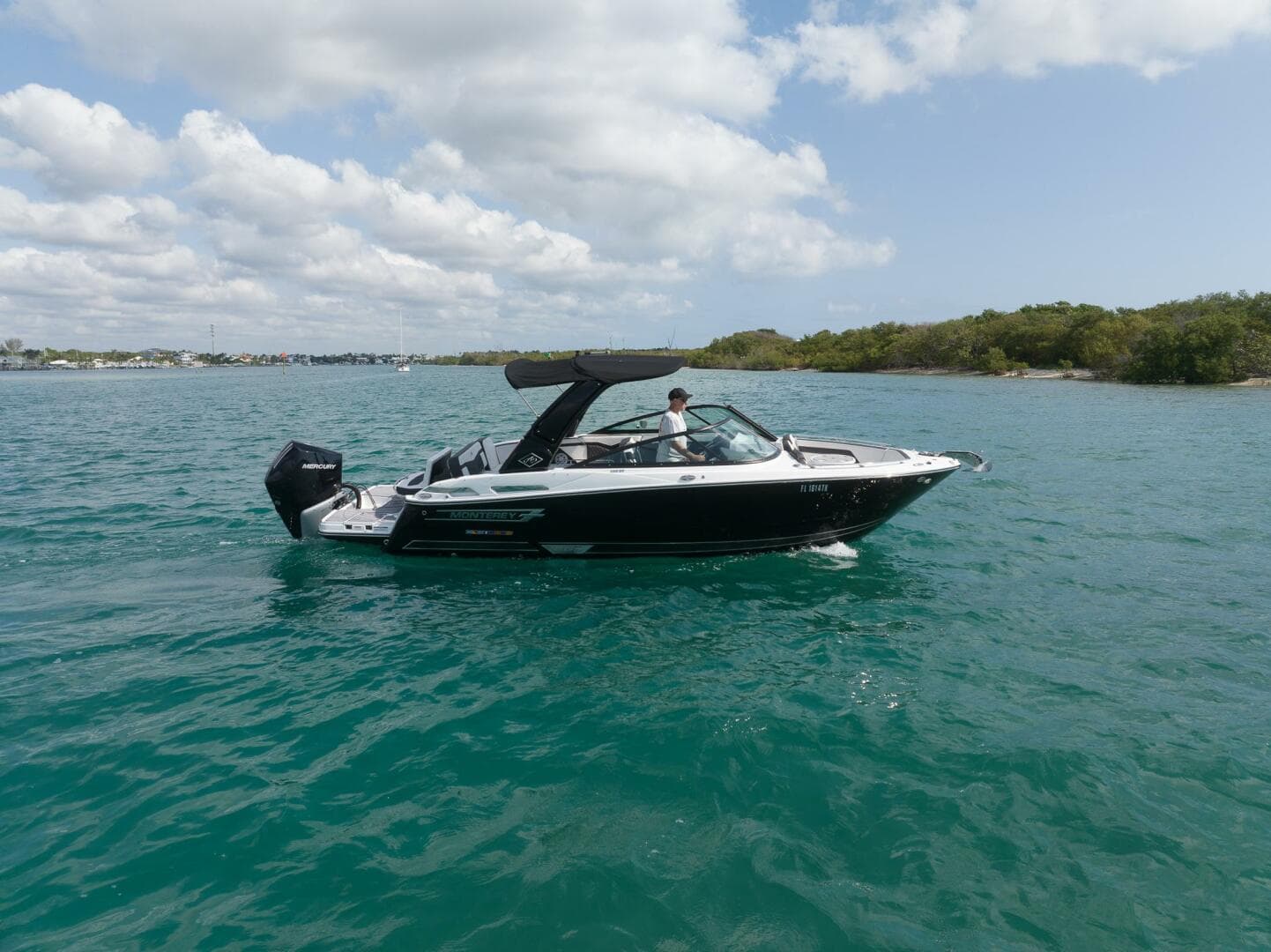 2023 Monterey 255 Super Sport boat cruising on clear blue water under a partly cloudy sky.