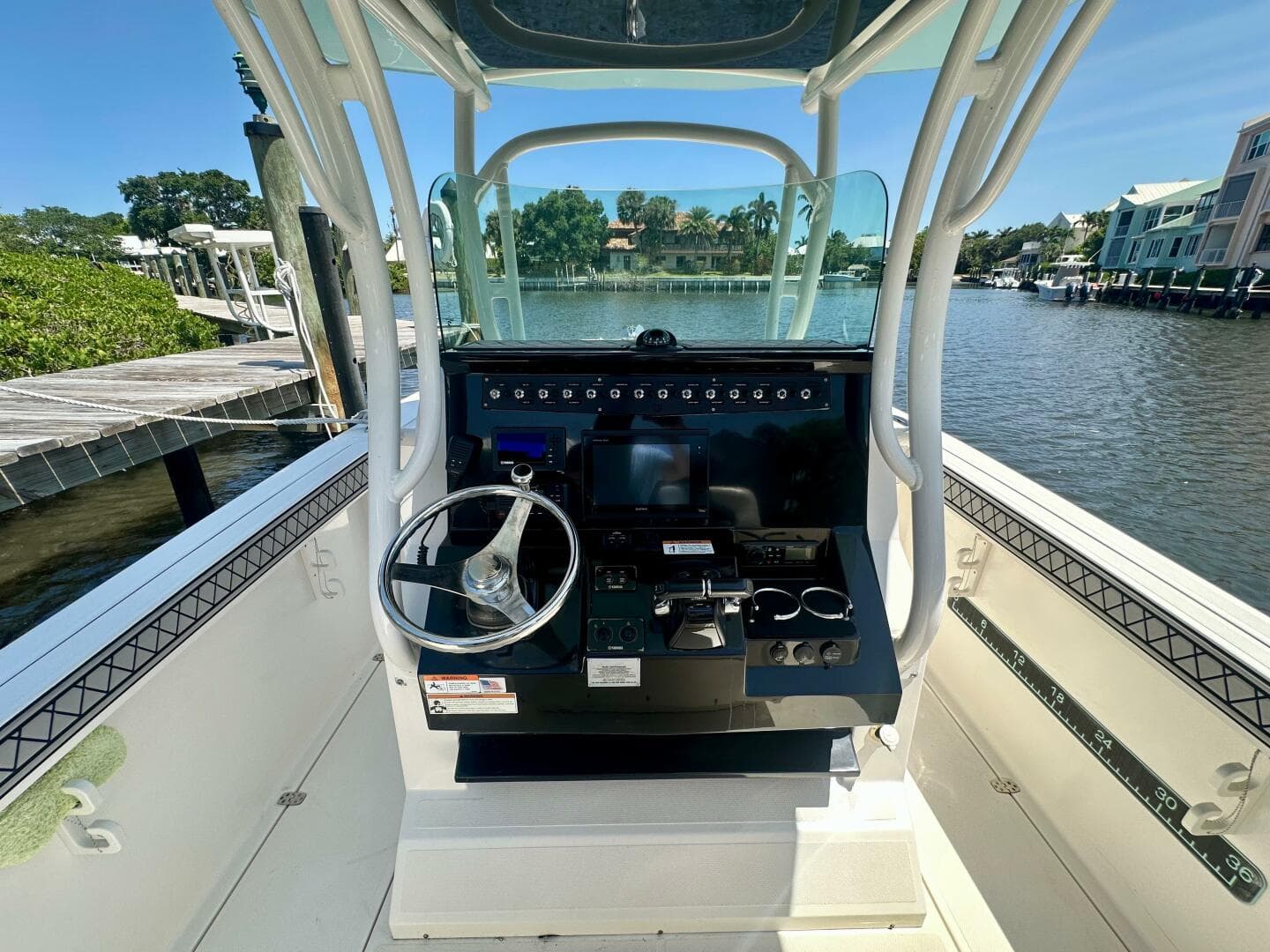 2019 Wellcraft 262 Fisherman boat console with steering wheel, docked by a scenic waterfront.
