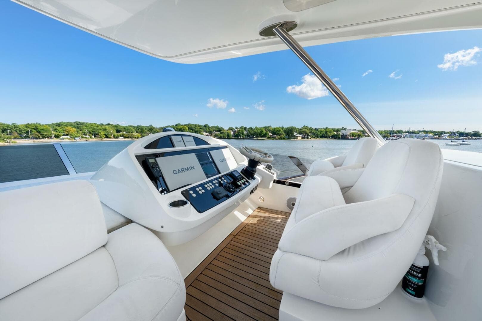 2016 Sunseeker Manhattan 65 yacht helm with white seating and navigation controls, overlooking water.