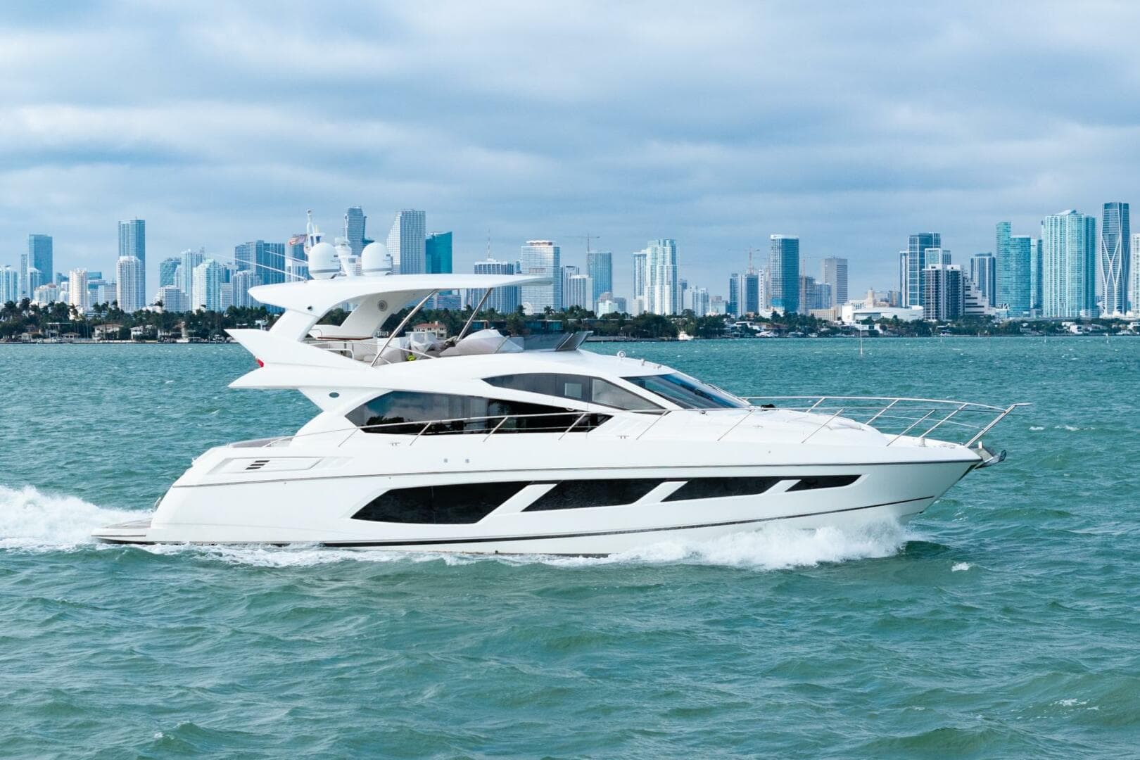 2016 Sunseeker Manhattan 65 yacht cruising with city skyline in the background.
