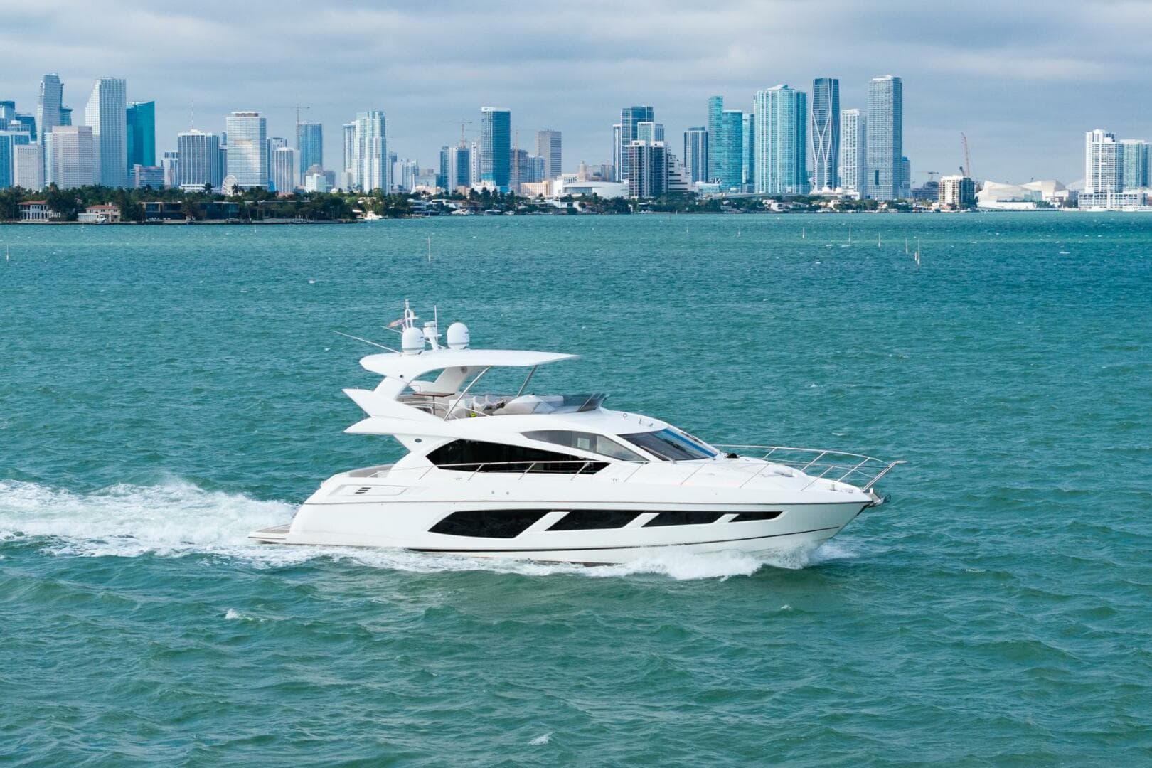 2016 Sunseeker Manhattan 65 yacht cruising near a city skyline.