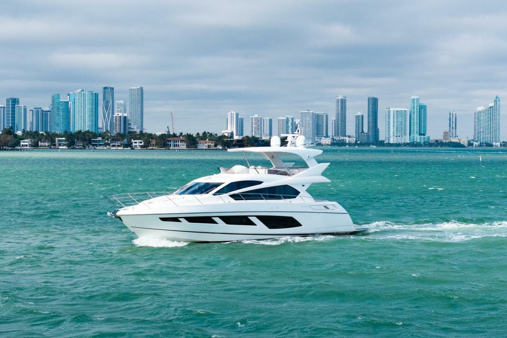 2016 Sunseeker Manhattan 65 yacht cruising near a city skyline.