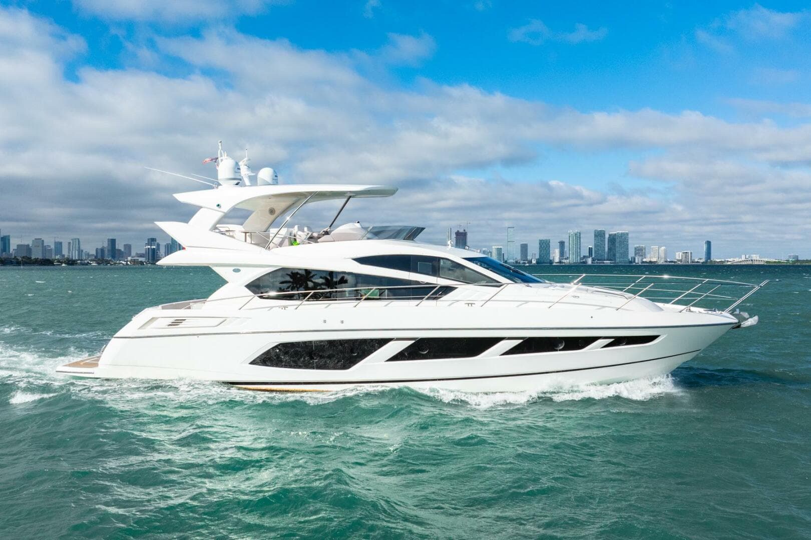 2016 Sunseeker Manhattan 65 yacht cruising on open water with city skyline backdrop.