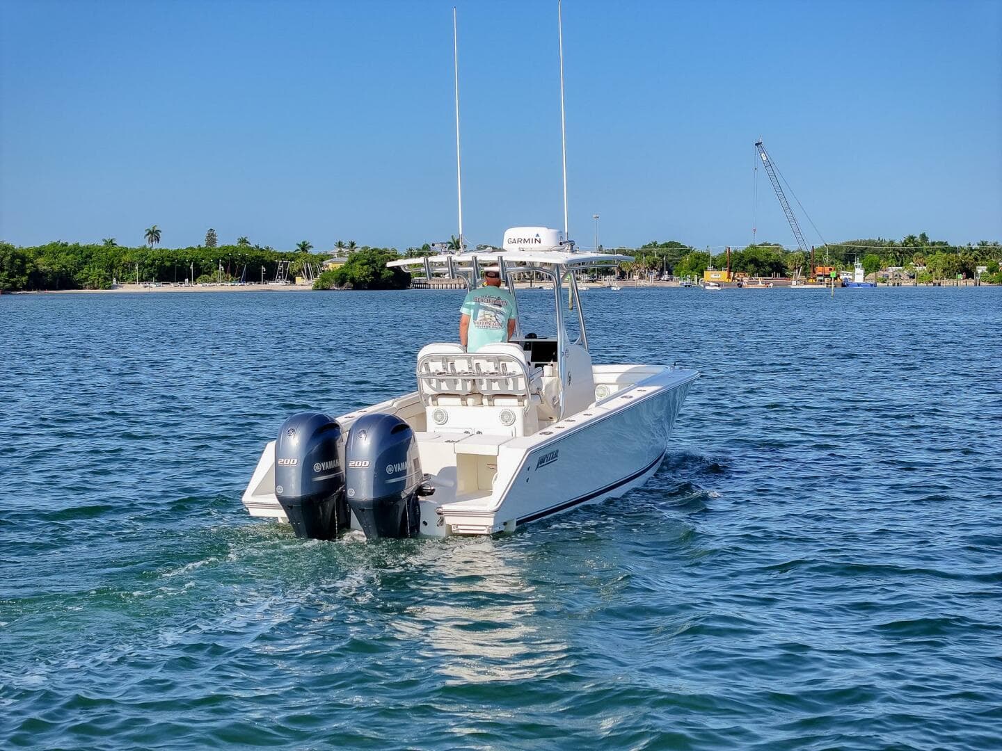 2018 Jupiter 26 FS boat cruising on clear blue water near a lush shoreline.