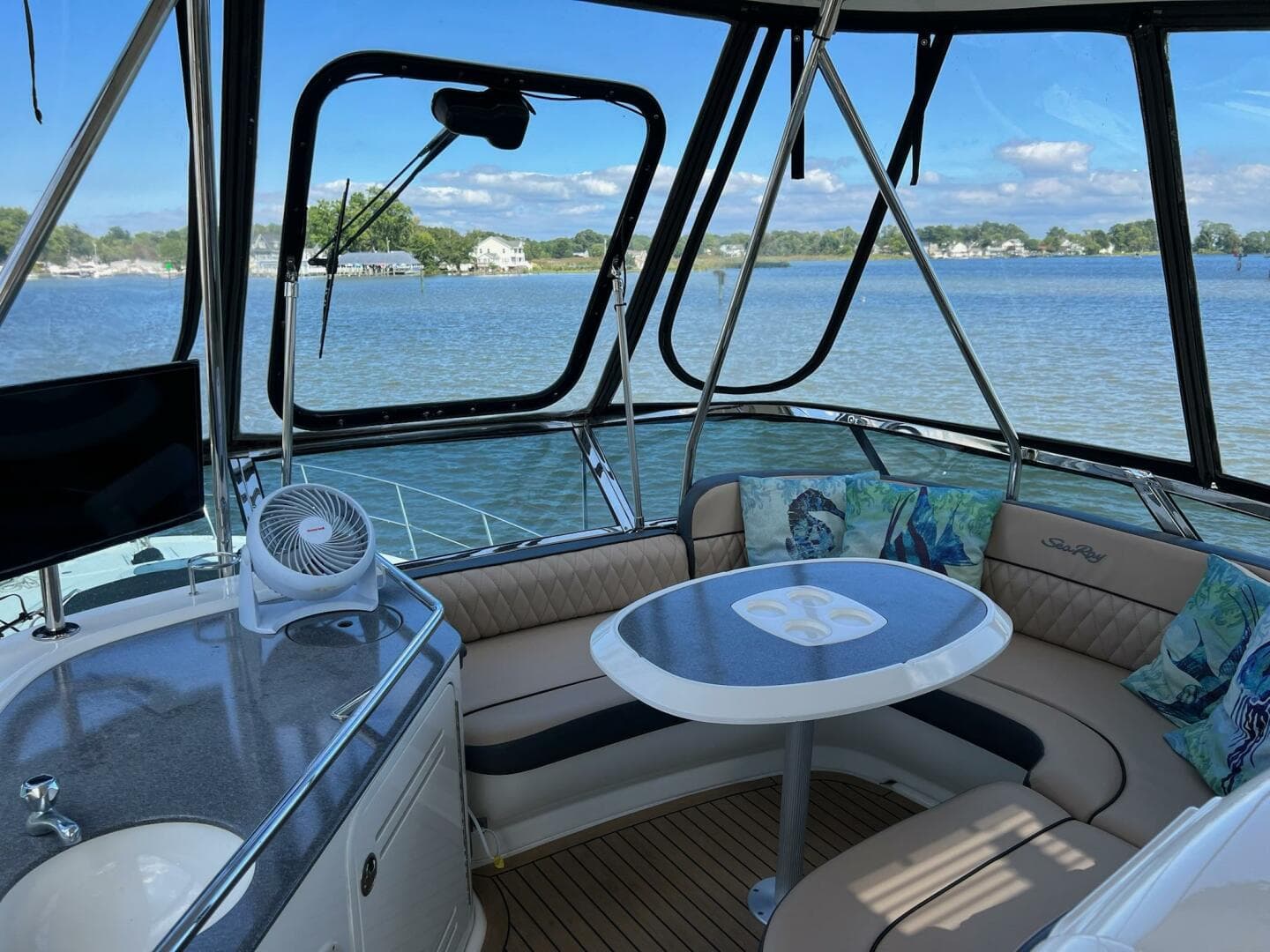 2005 Sea Ray 500 Sedan Bridge interior with seating and table, overlooking serene water view.
