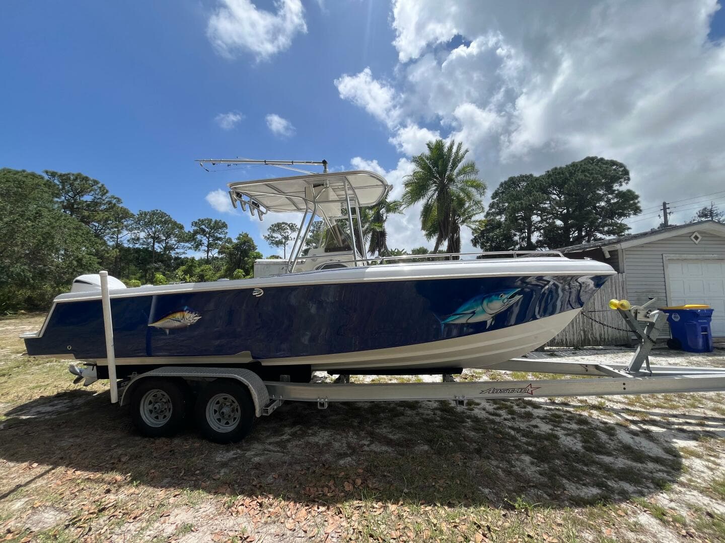 1998 Blue Fin 25 Center Console boat on trailer, parked outdoors under cloudy sky.