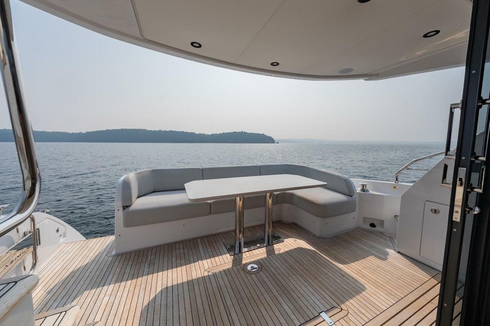 Luxury Azimut Fly 53 yacht deck with seating, overlooking serene water and distant shoreline.