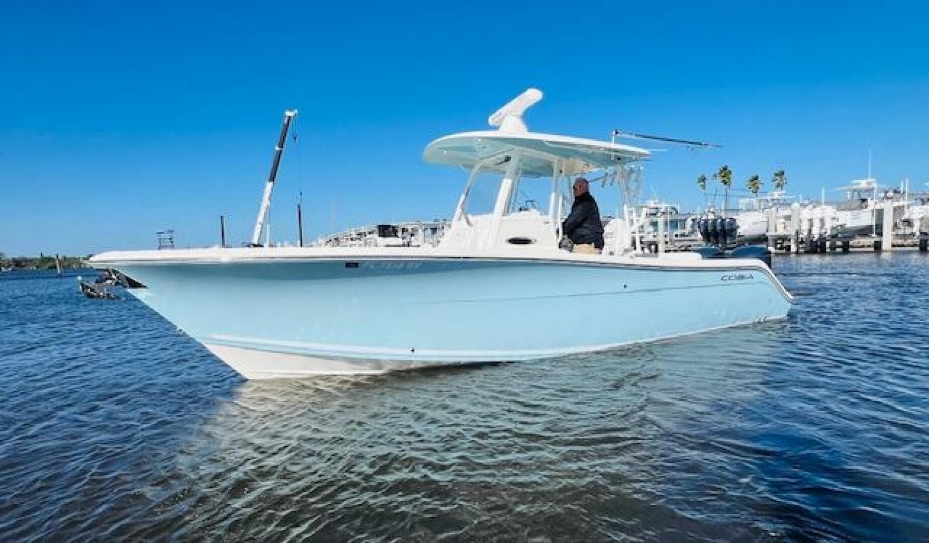 2021 Cobia 301 Center Console boat on calm water, clear blue sky background.