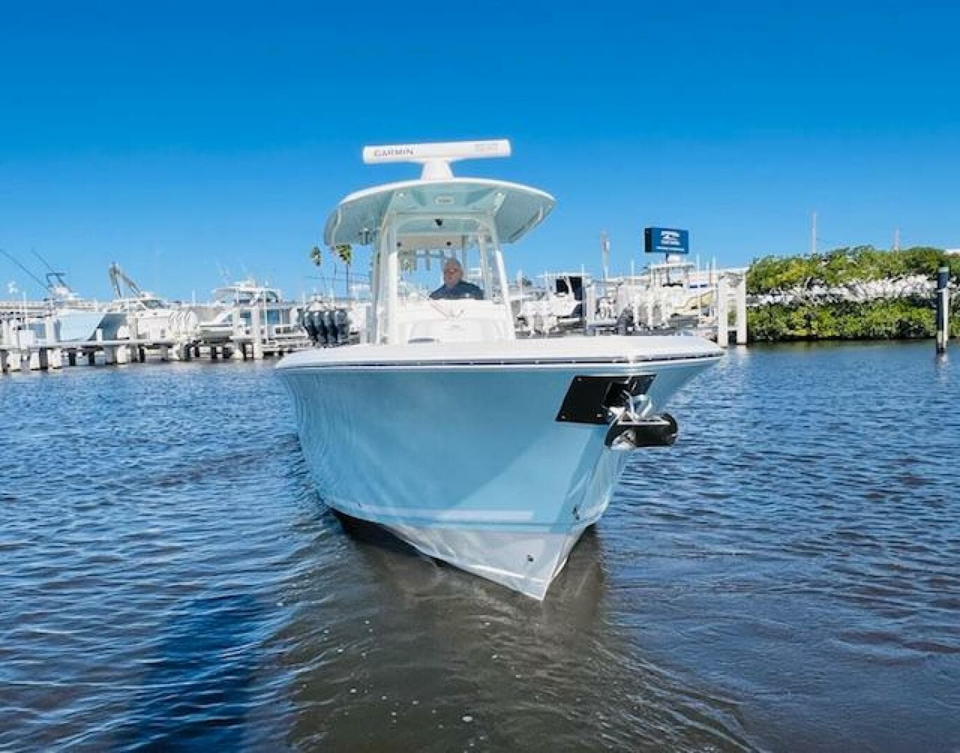 2021 Cobia 301 Center Console boat on water near marina under clear blue sky.