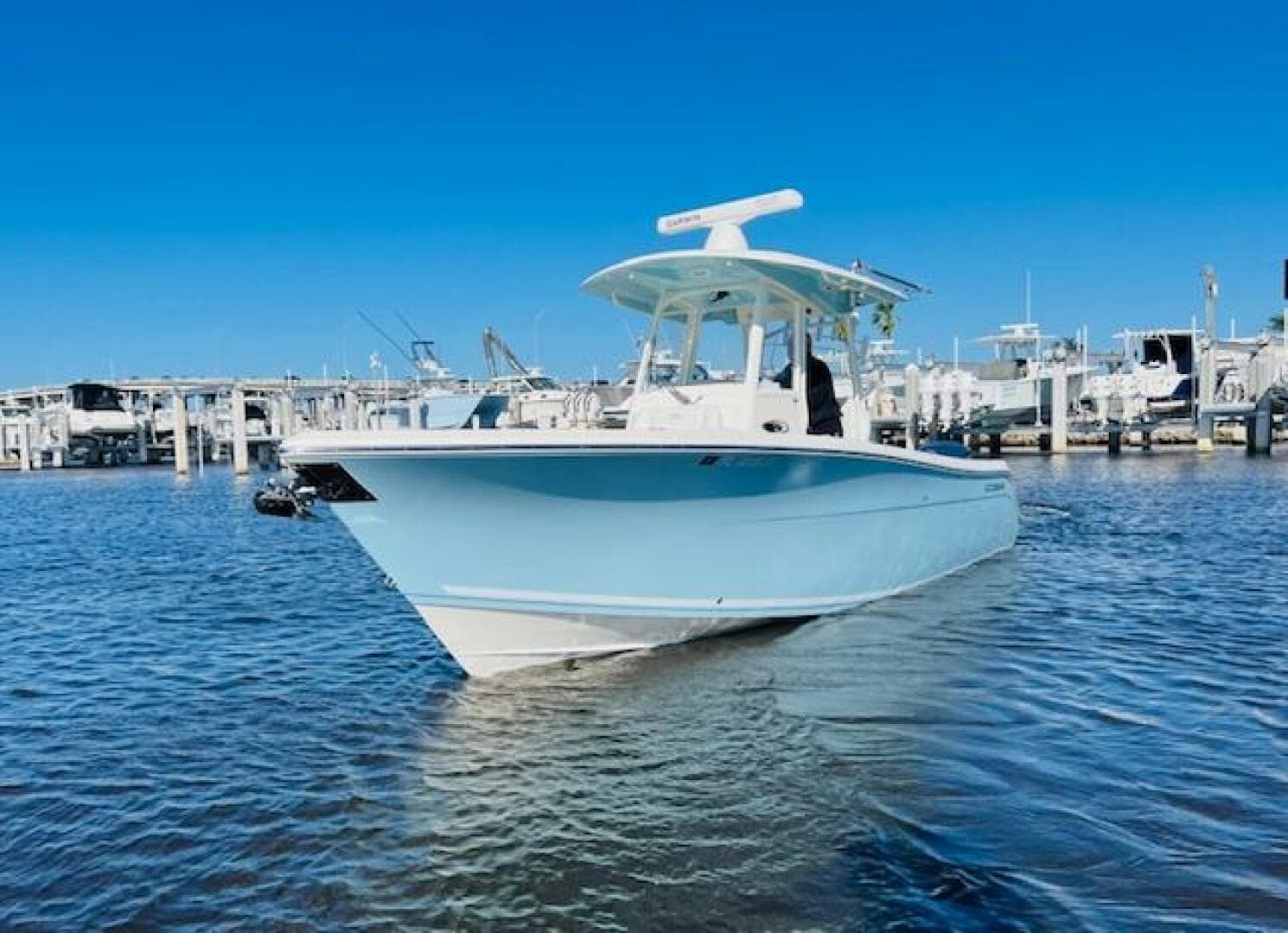 2021 Cobia 301 Center Console boat docked in marina under clear blue sky.