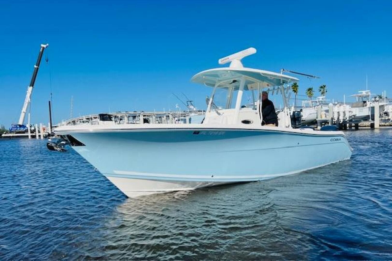 2021 Cobia 301 Center Console boat on water, clear blue sky background.