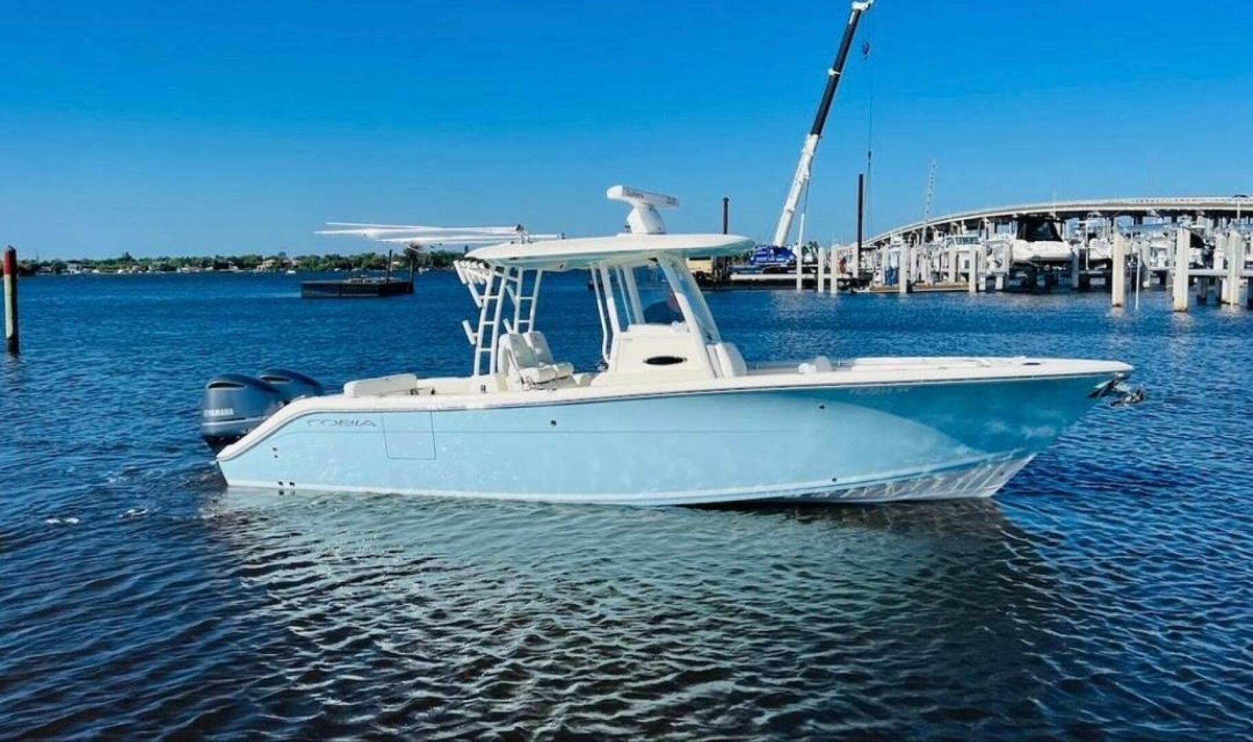 2021 Cobia 301 Center Console boat on water near a marina.