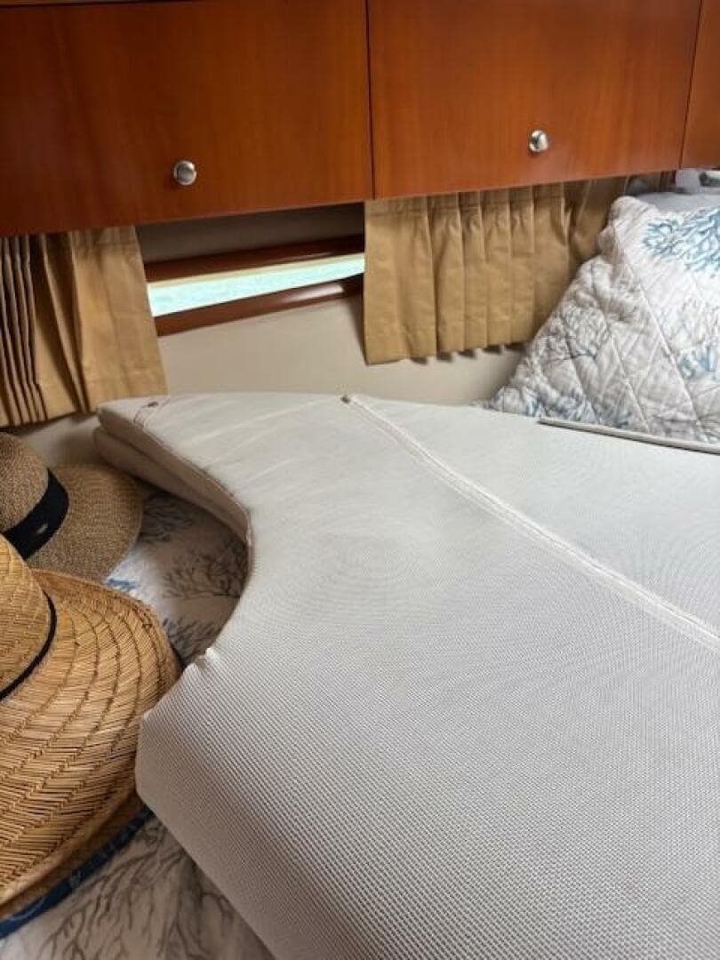 Interior of 2006 Carver 43 Motor Yacht with bed, pillows, and straw hats.