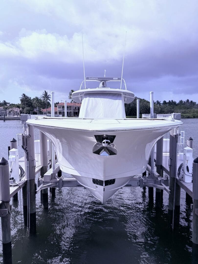 2024 Scout 400 LXF boat docked, front view with water and cloudy sky background.
