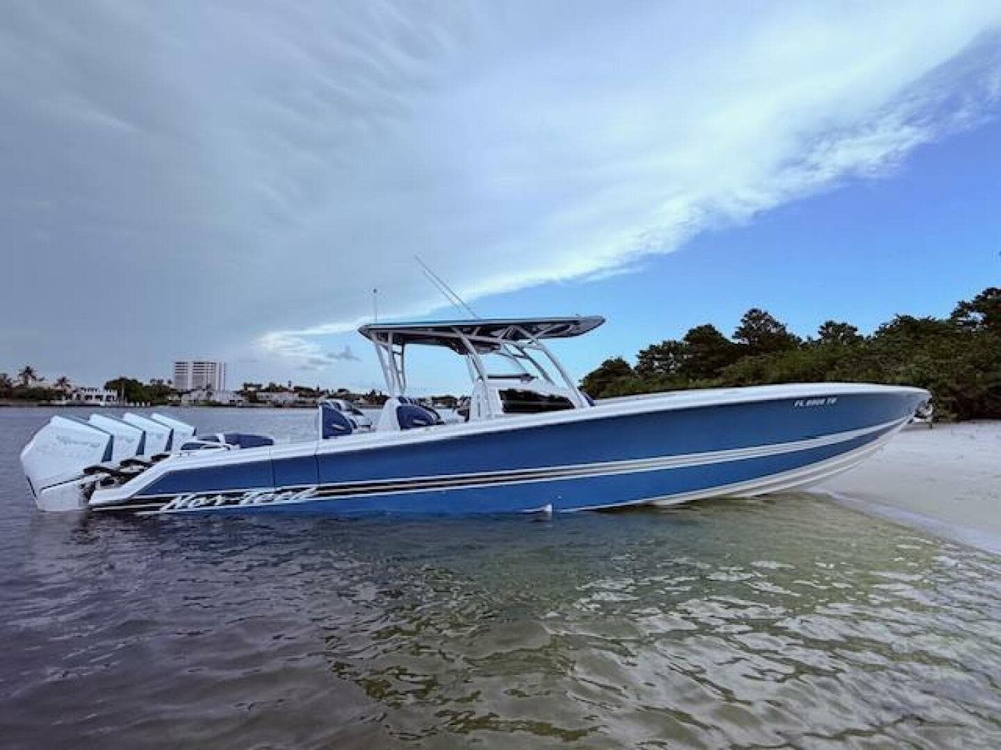 2022 Nor-Tech 390 Sport Center Console boat on a sandy beach with cloudy sky.