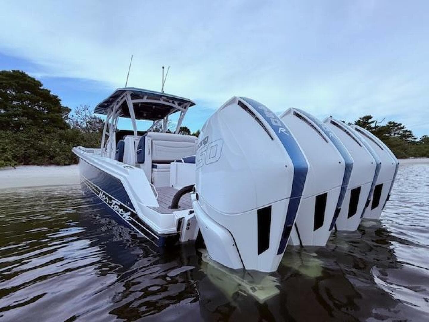 2022 Nor-Tech 390 Sport Center Console boat with multiple outboard engines in shallow water.