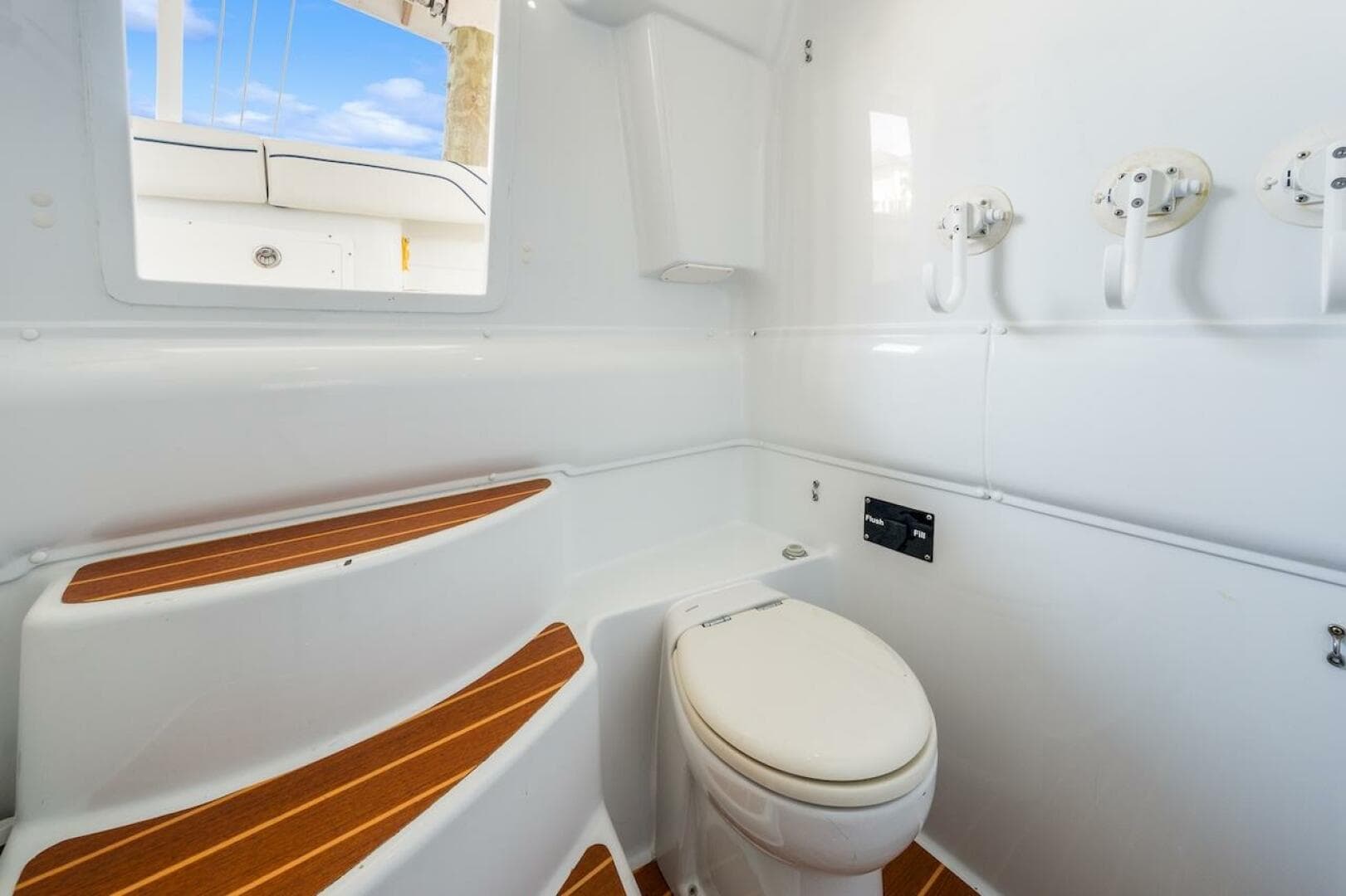 Interior of 2015 Yellowfin 39 boat featuring a compact marine toilet and wooden steps.