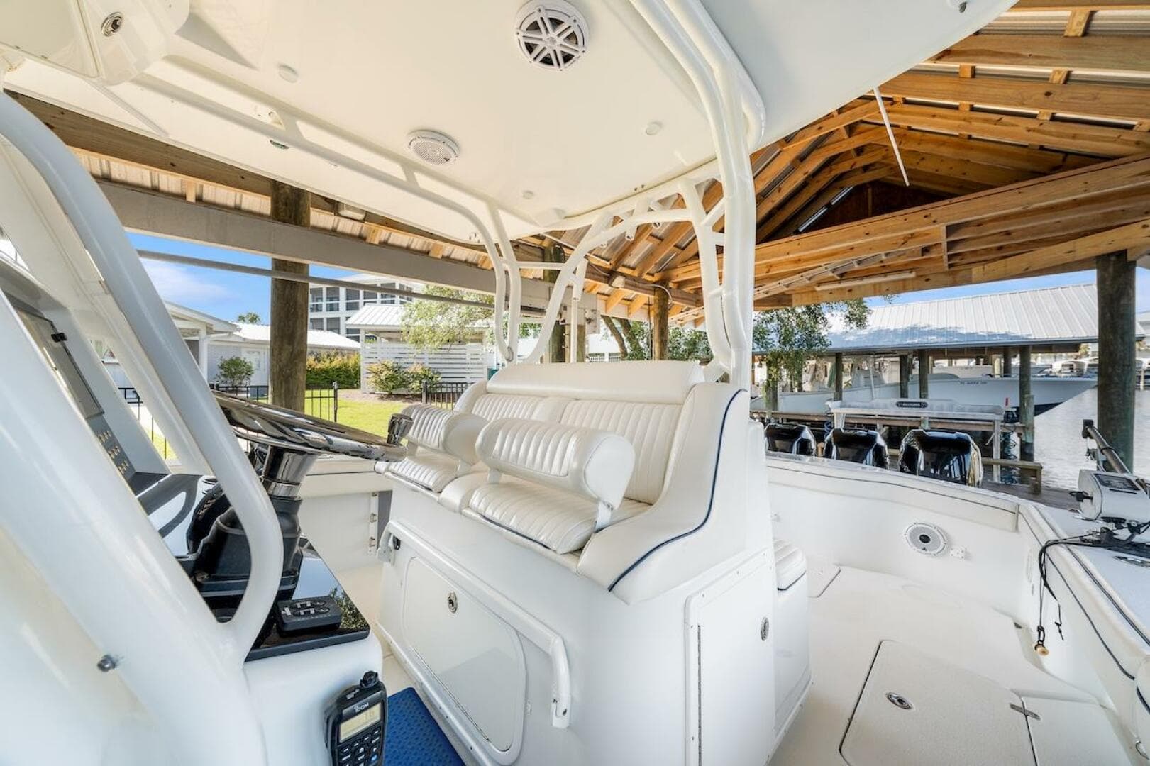 2015 Yellowfin 39 boat interior with white seating and helm under a wooden dock shelter.