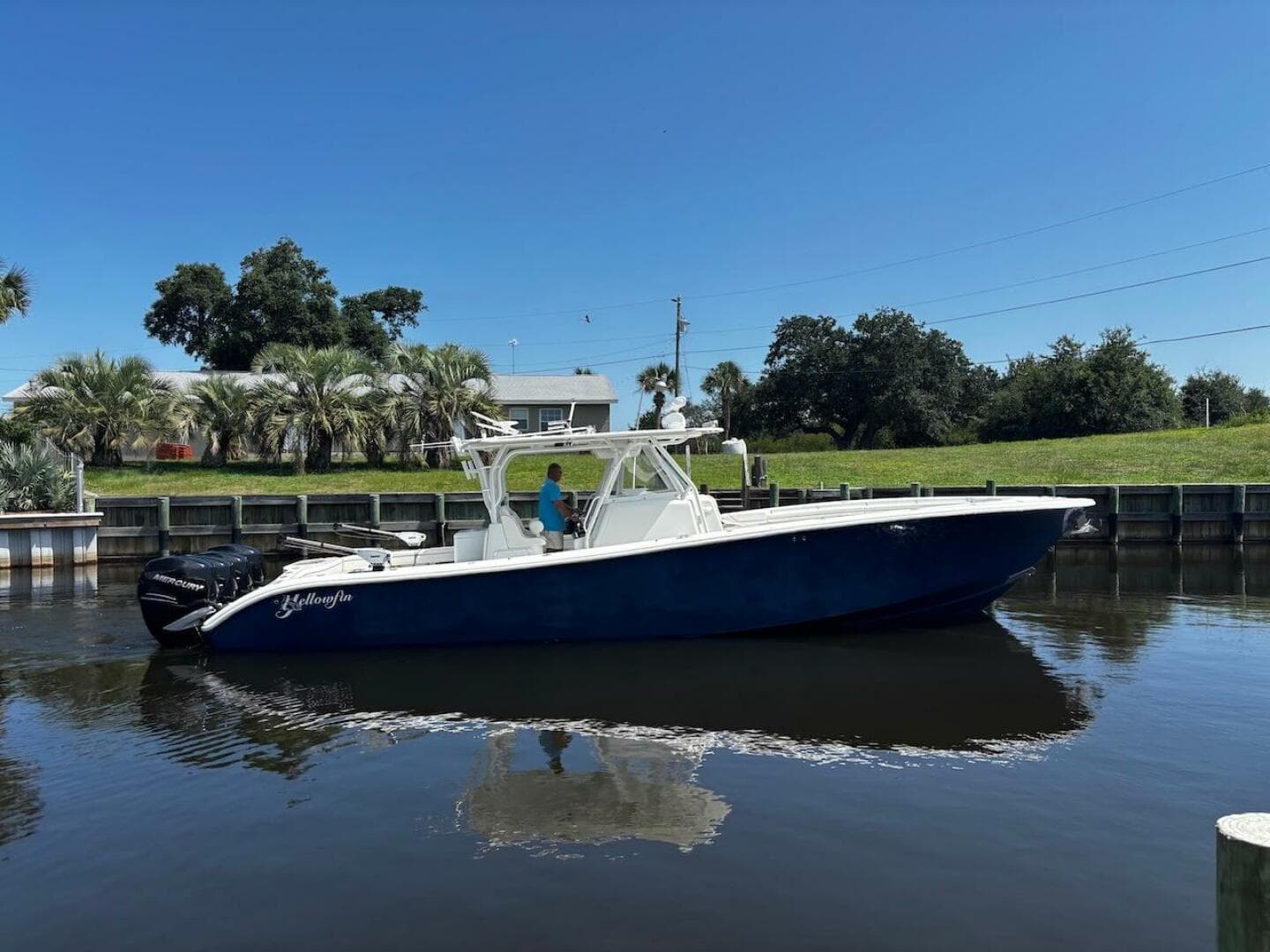 2015 Yellowfin 39 boat on calm water, clear sky, and lush greenery in the background.