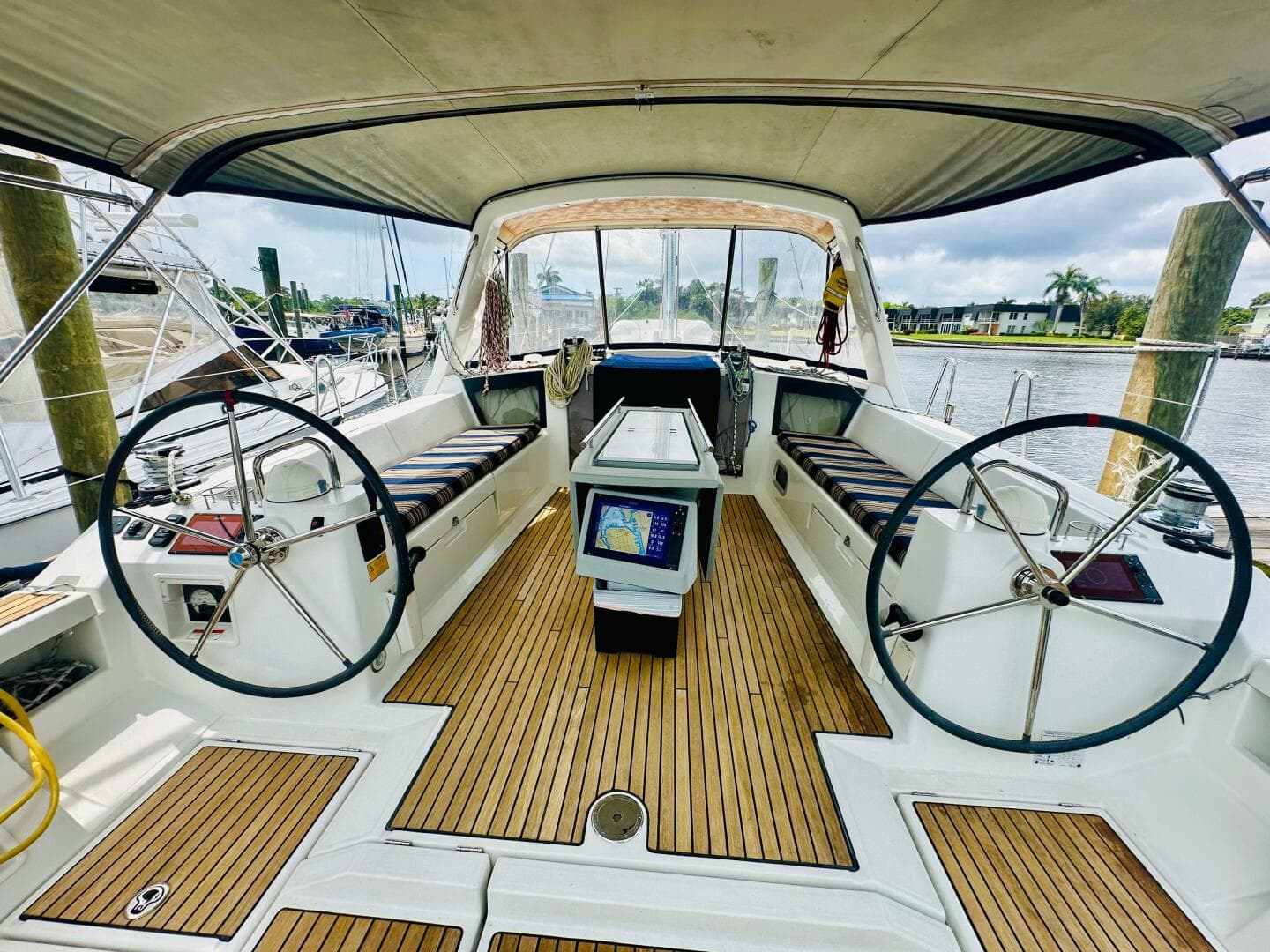 Cockpit of 2015 Beneteau Oceanis 45 sailboat with dual steering wheels and teak flooring.