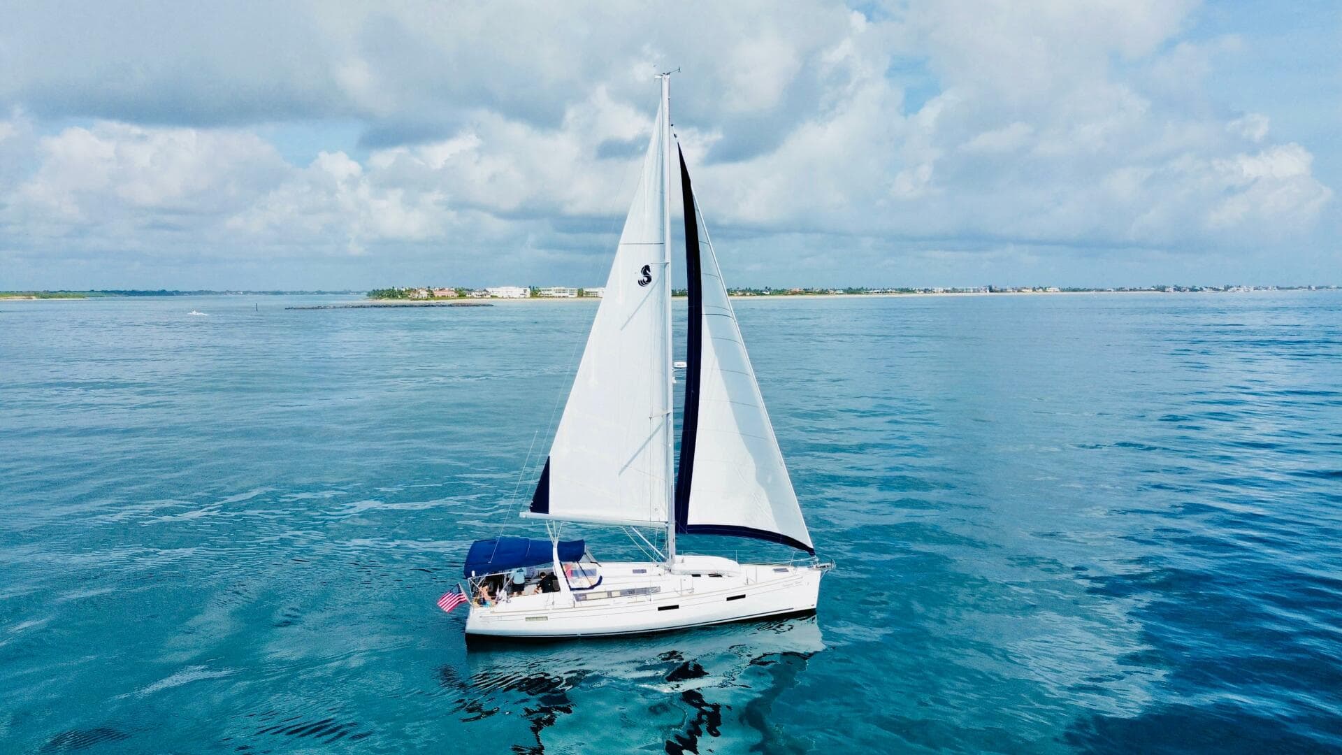 2015 Beneteau Oceanis 45 sailing on calm blue waters under a cloudy sky.