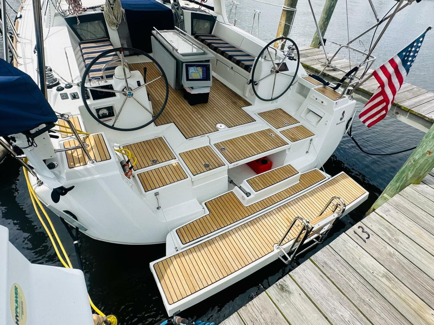 2015 Beneteau Oceanis 45 sailboat with dual steering wheels, docked with American flag.