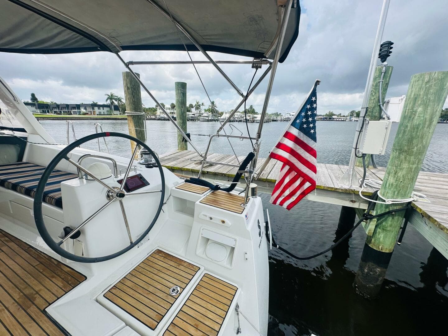Beneteau Oceanis 45 sailboat cockpit with American flag, docked by a marina.