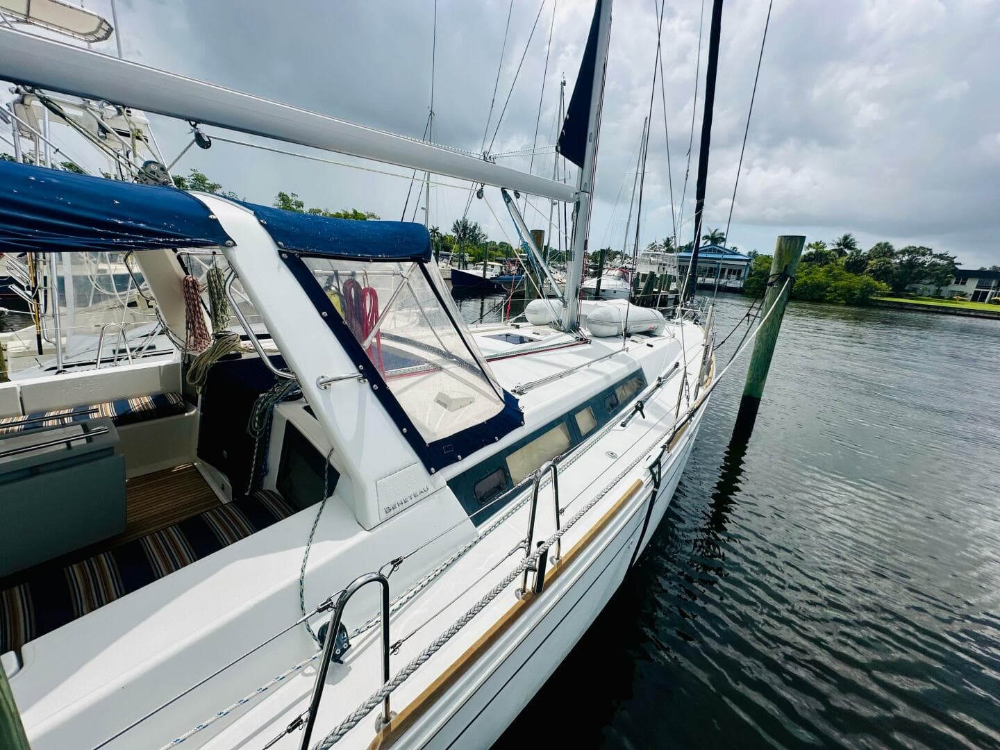2015 Beneteau Oceanis 45 sailboat docked on a calm waterway under cloudy skies.
