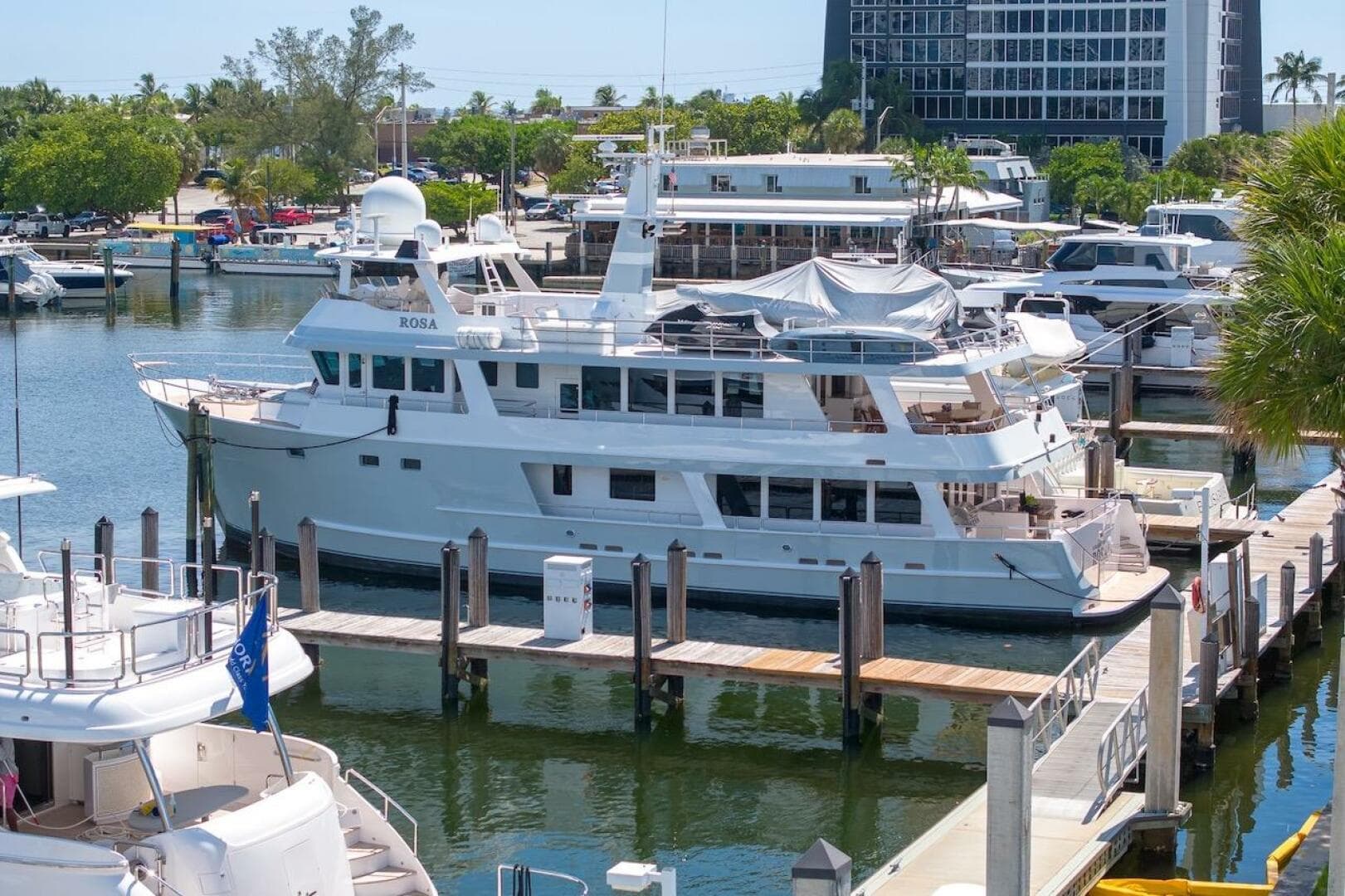 Luxury yacht ABD 90 Explorer 1996 docked at marina, surrounded by other boats and lush greenery.