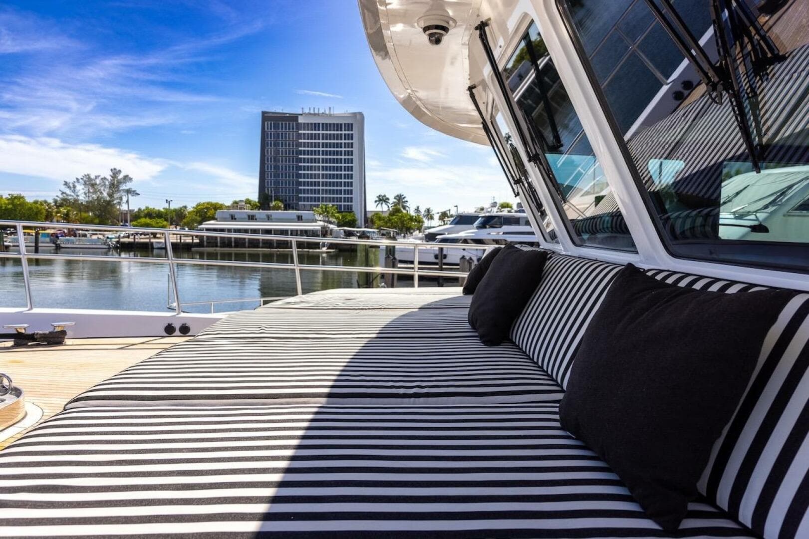 Luxurious ABD 90 Explorer yacht with striped seating, docked near a waterfront building.