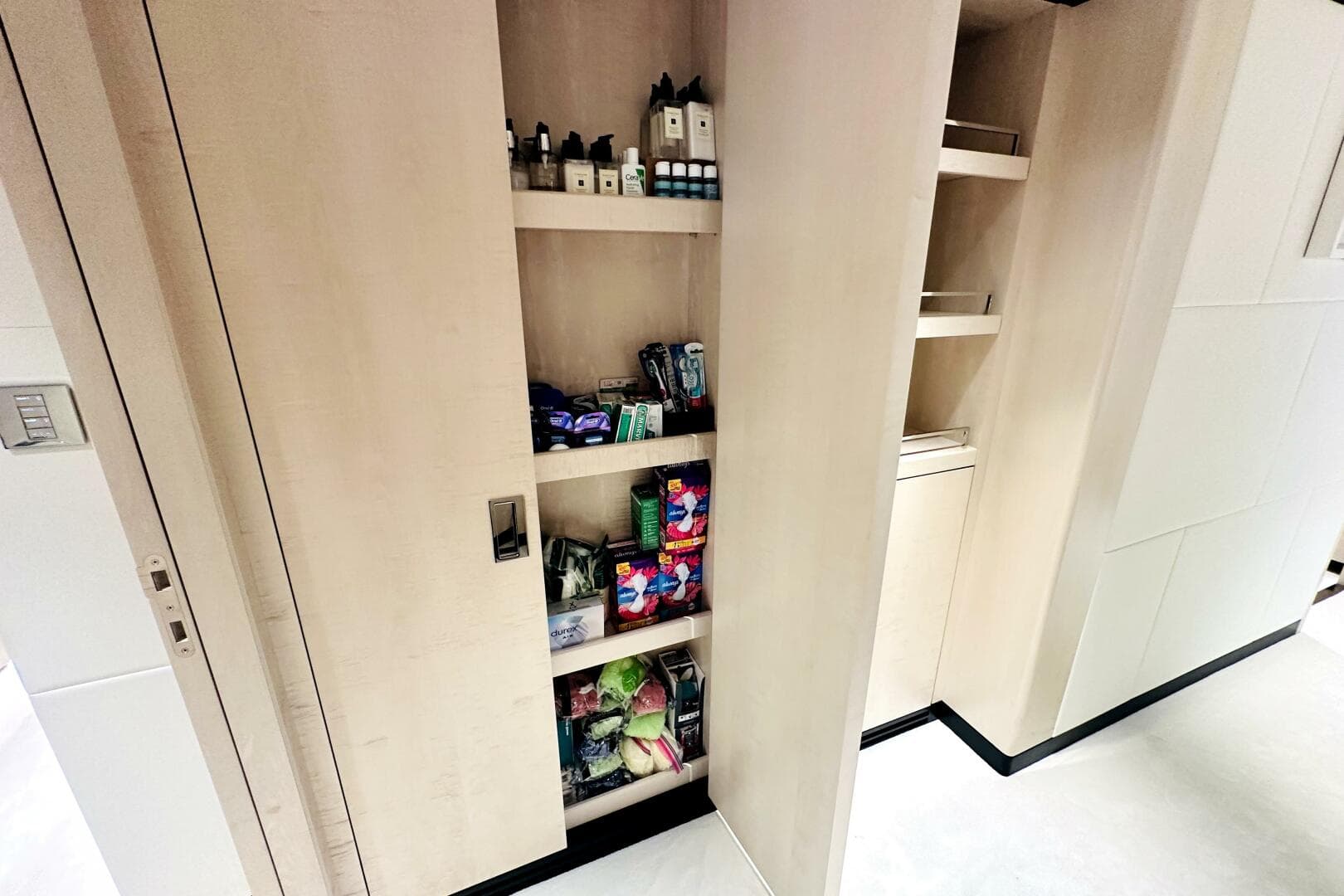 Modern pantry shelves in a 2023 Majesty 120 yacht, stocked with toiletries and snacks.