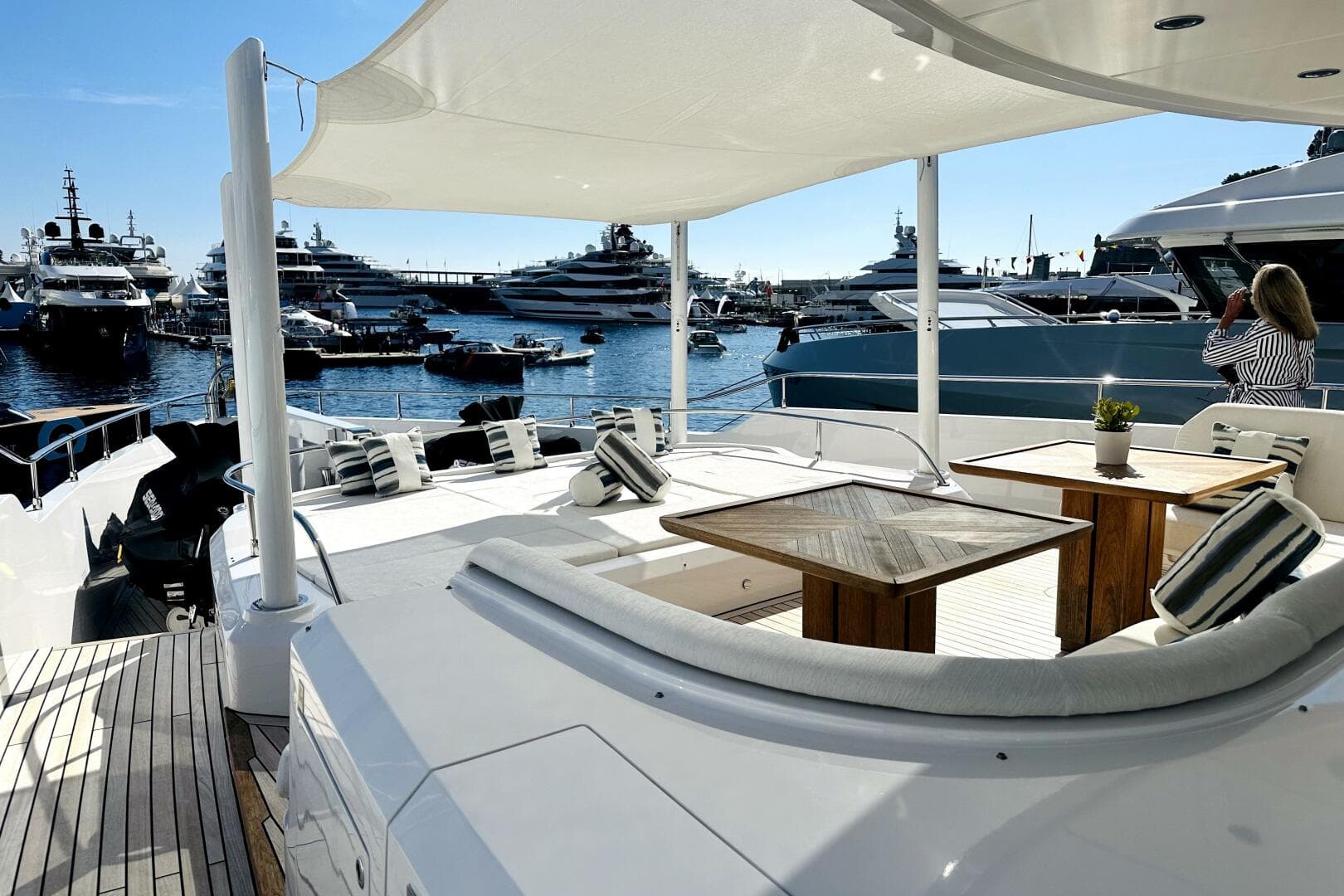 Luxurious 2023 Majesty 120 yacht deck with elegant seating, overlooking marina filled with yachts.