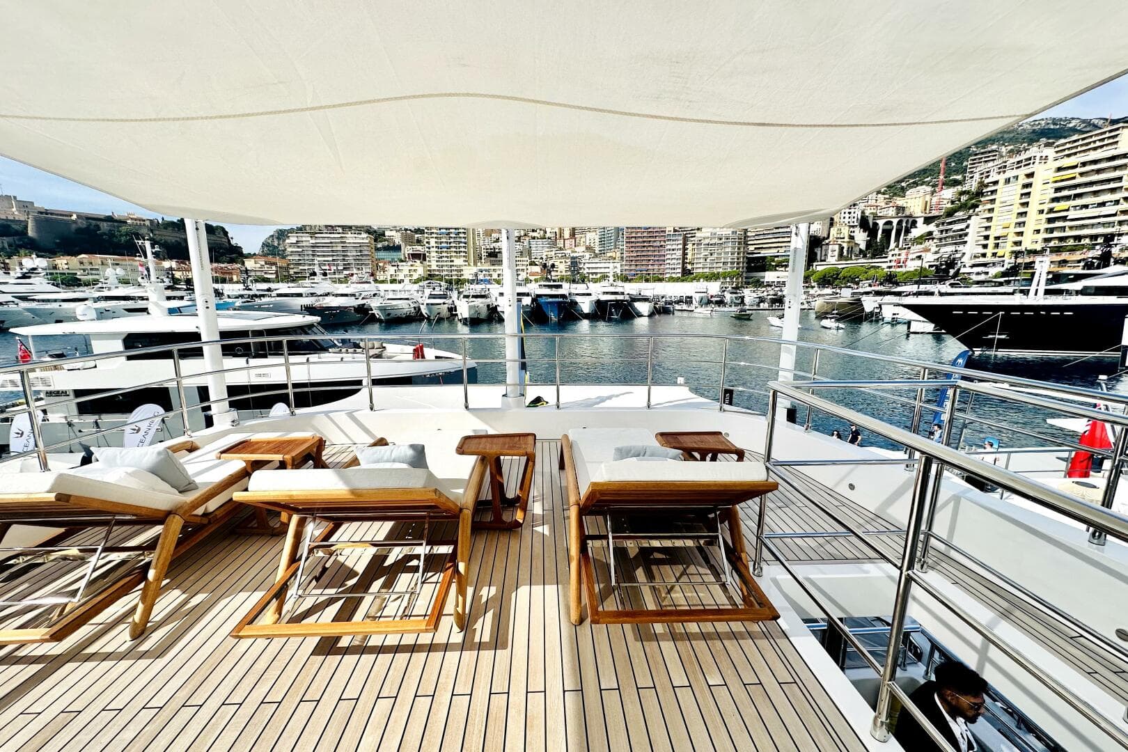 Luxurious 2023 Majesty 120 yacht deck with sun loungers, overlooking a marina.