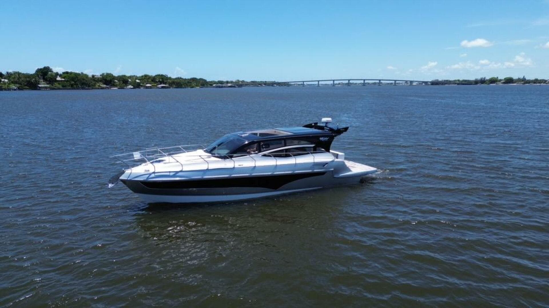 2025 Real 40 HT Luxury yacht cruising on a calm river under a clear blue sky.