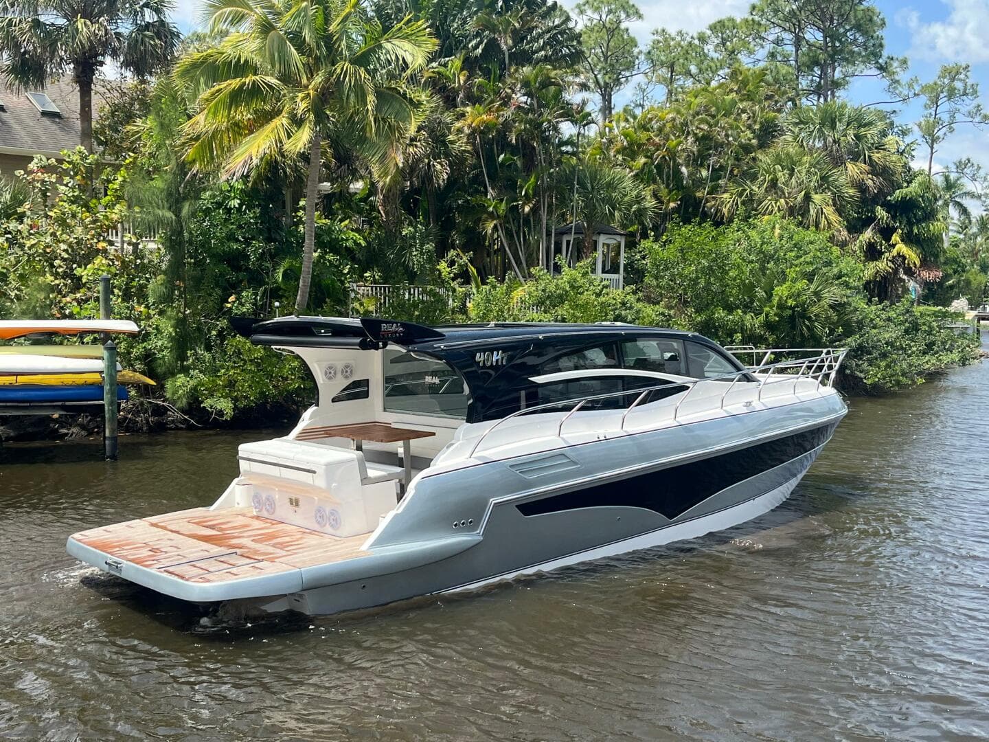 2025 Real 40 HT Luxury yacht cruising on a scenic river with lush greenery.