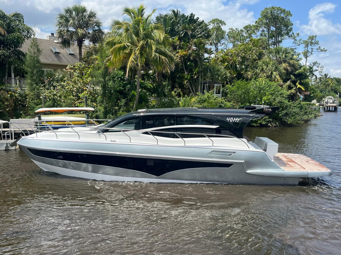 2025 Real 40 HT Luxury yacht on a river, surrounded by lush greenery and palm trees.