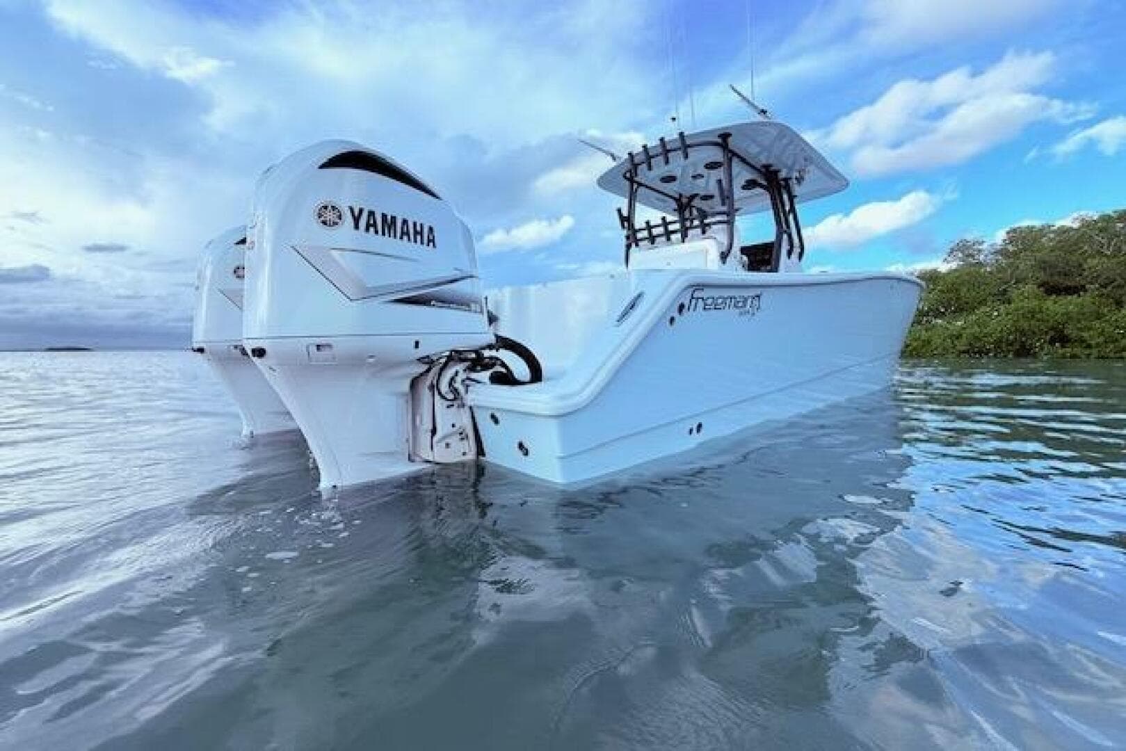 2019 Freeman 34 boat with Yamaha engines on calm water under a cloudy sky.