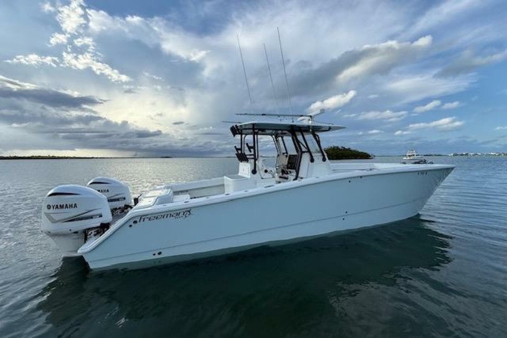 2019 Freeman 34 boat with Yamaha engines on calm water under a cloudy sky.