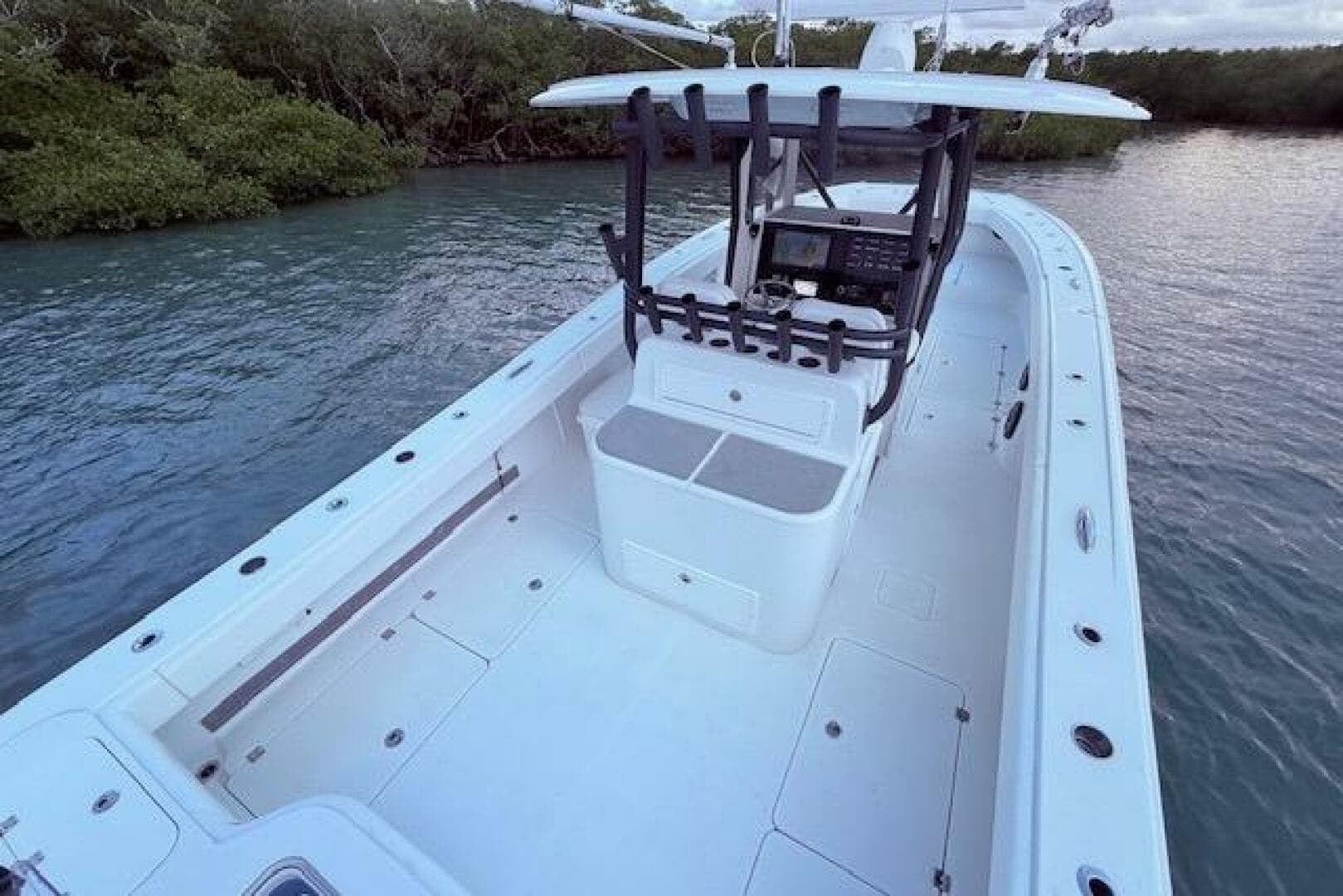 2019 Freeman 34 boat with spacious deck and modern console, docked near lush greenery.