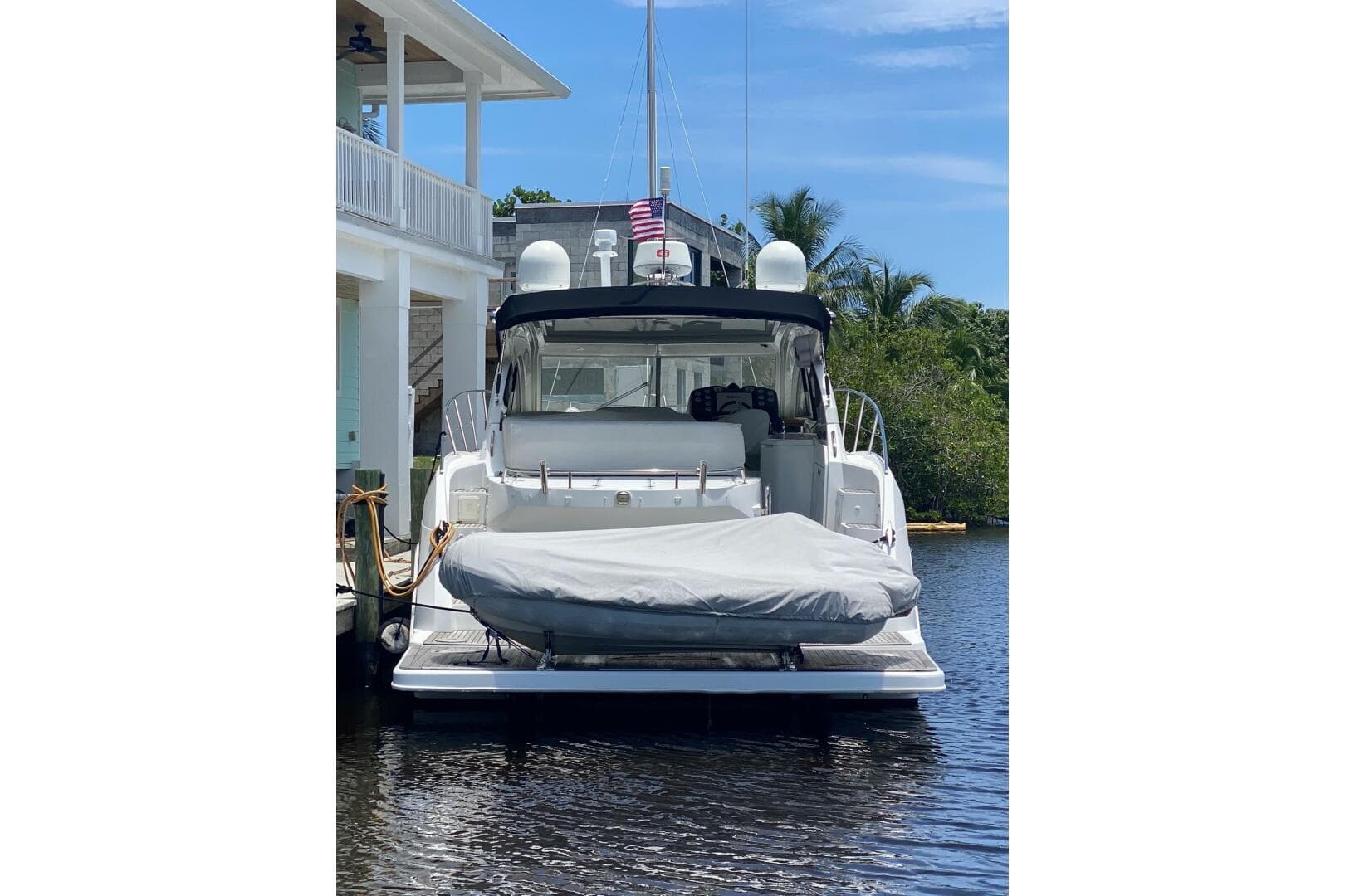 2014 Beneteau Gran Turismo 44 yacht docked, rear view with covered equipment, blue sky background.