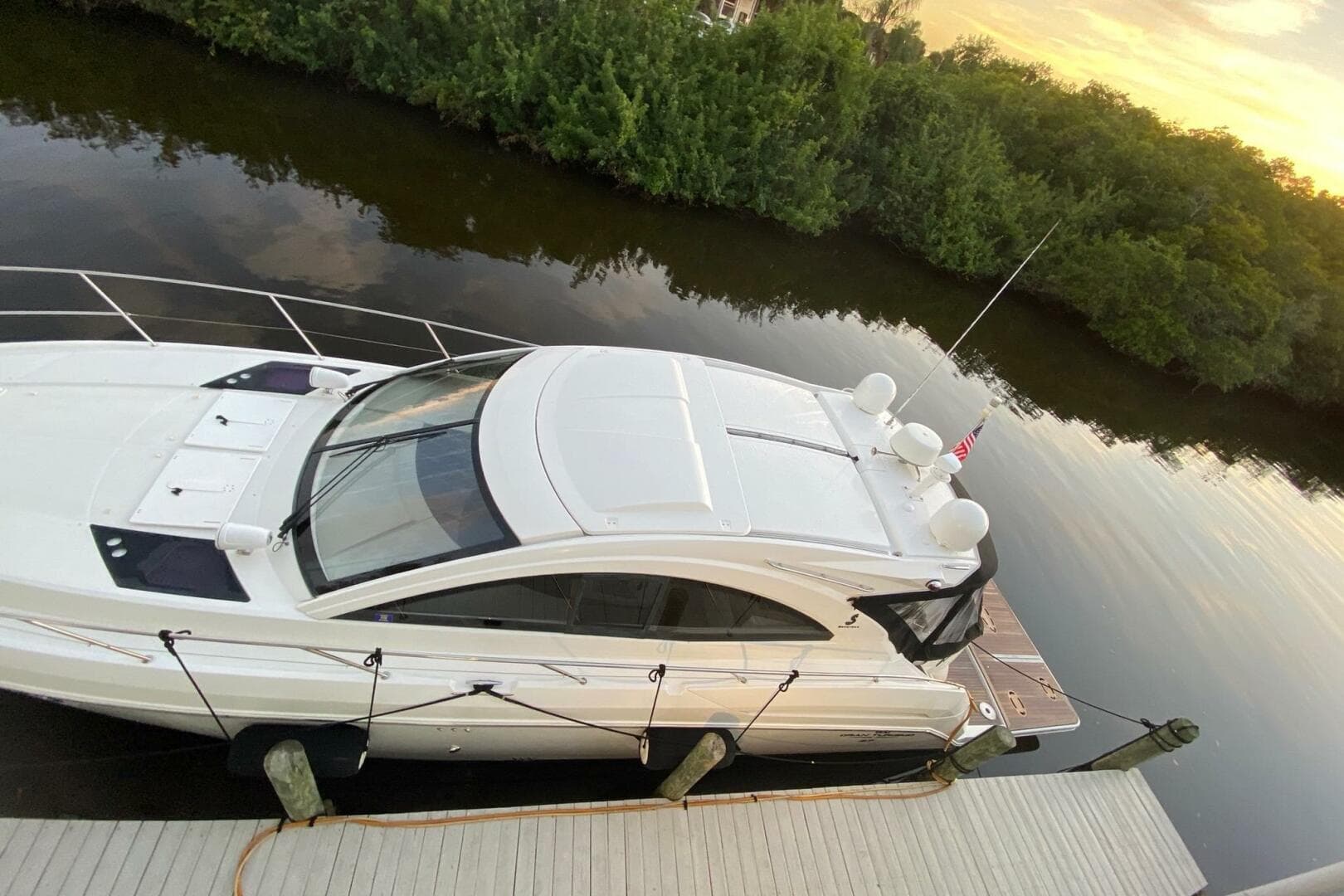 2014 Beneteau Gran Turismo 44 yacht docked by a serene riverbank at sunset.