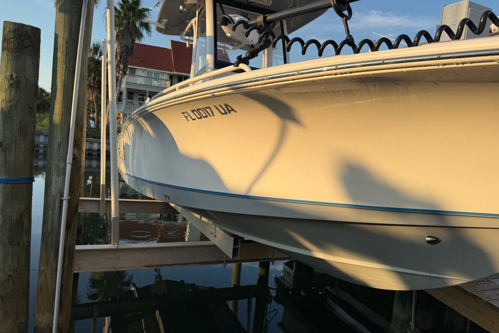 2018 Sea Hunt BX 25 FS boat docked, reflecting sunlight, with palm trees in the background.