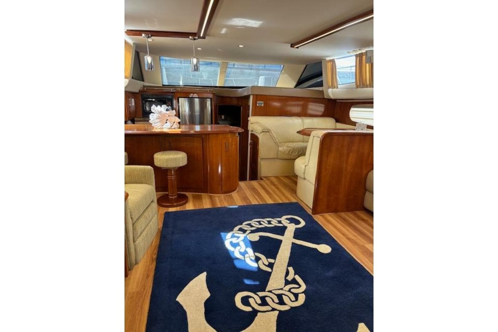 Luxurious interior of 2004 Carver 466 Motor Yacht with elegant wood finishes and anchor-themed rug.