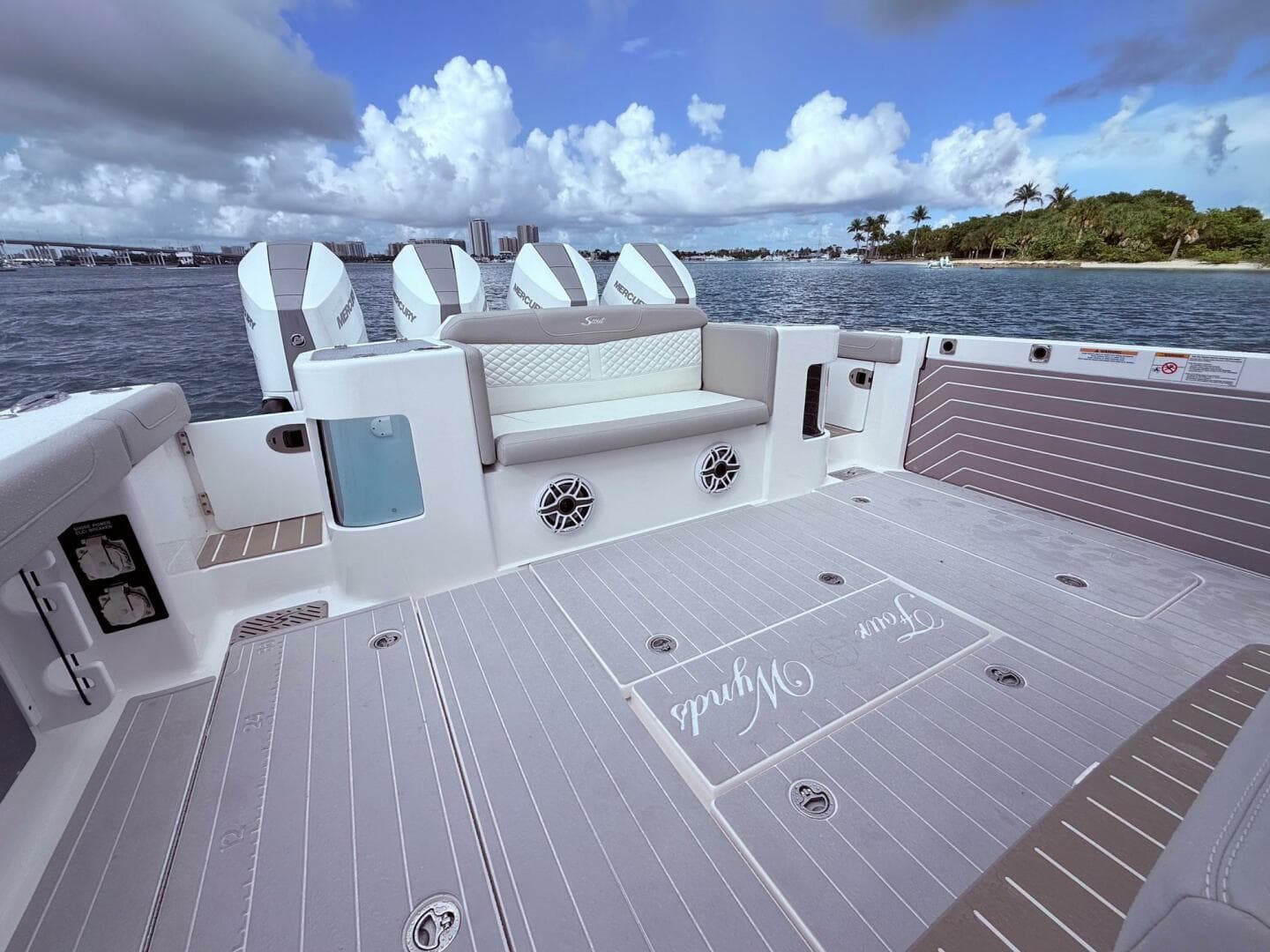 2024 Scout 400 LXF boat deck with seating, ocean view, and four outboard engines.