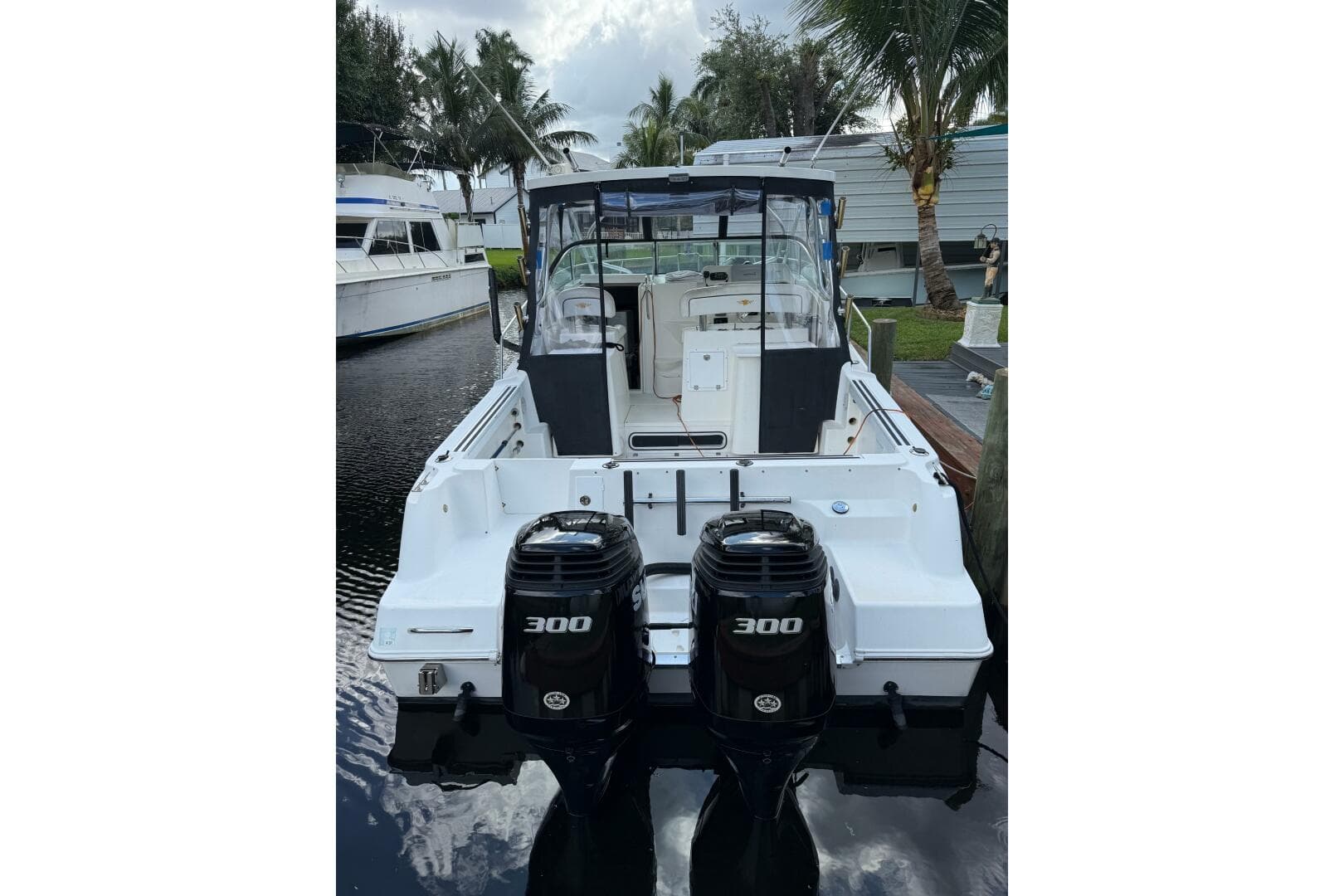 2002 Wellcraft 290 Coastal boat with dual 300 horsepower engines docked by palm trees.