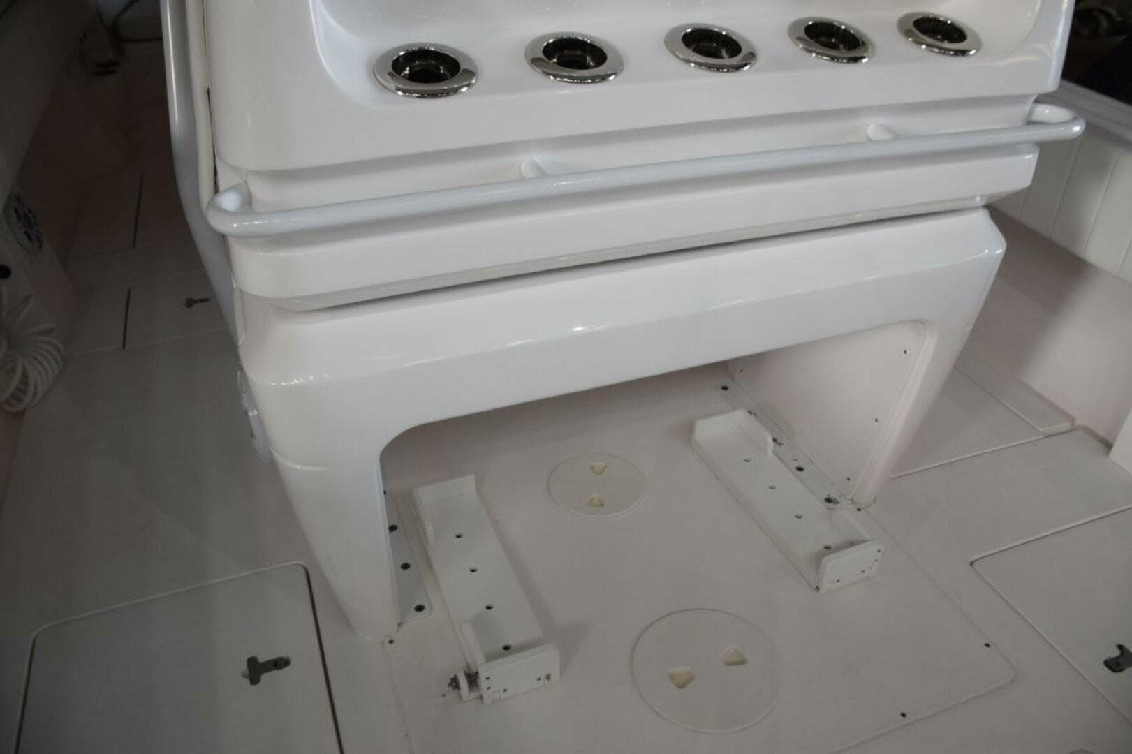 Behind Helm Seat Console, Drink Holder Or Rod Holders And Safety Grab Railing, Cooler Chocks Beneath.