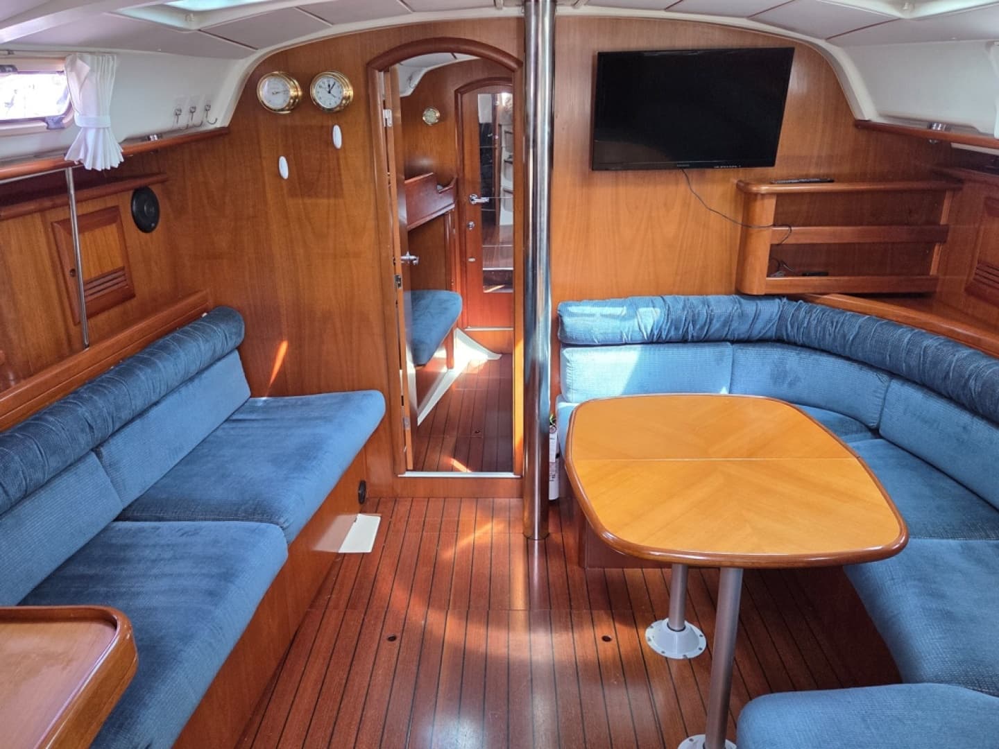 Interior of 2000 Beneteau Oceanis 411 yacht with blue upholstery and cherry wood finish