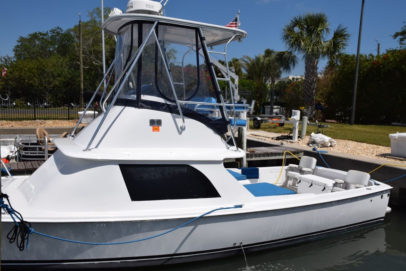 1976 Bertram Flybridge Cruiser Docked, Featuring Sleek Design And Spacious Deck Under Clear Blue Sky